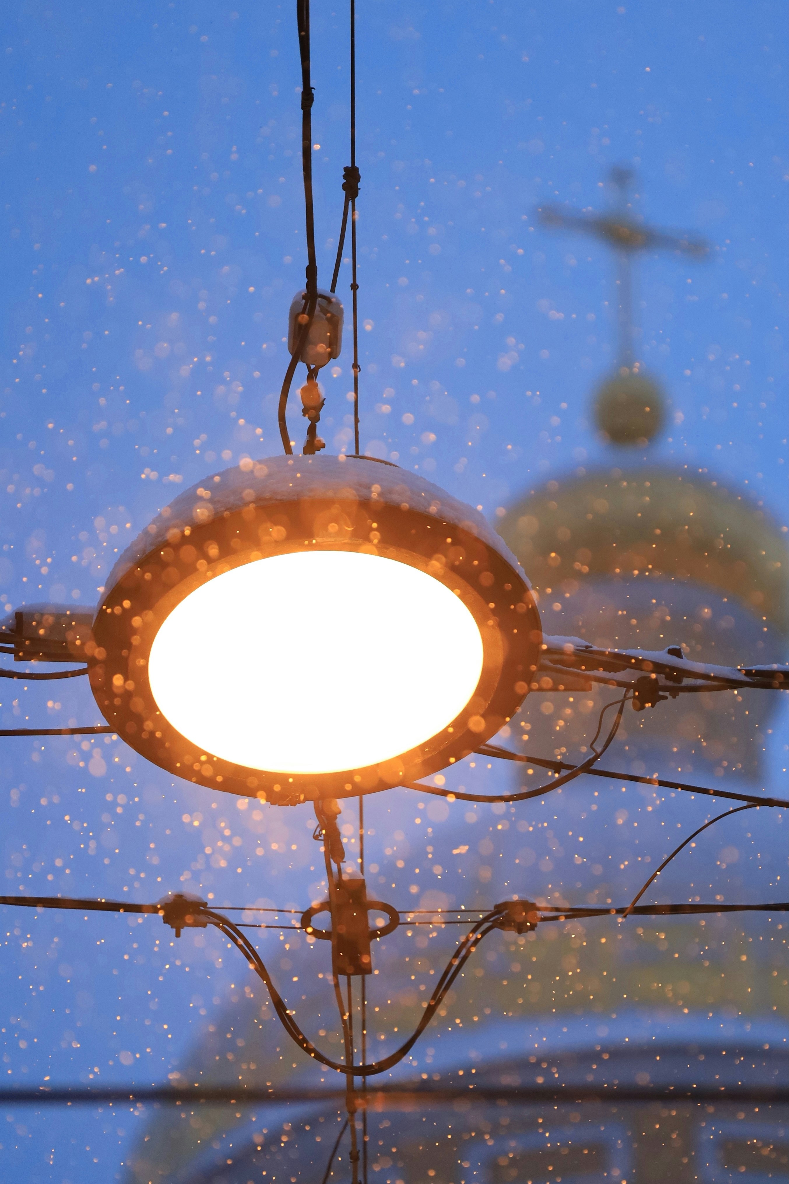 Die Straßenlaterne beleuchtet fallenden Schnee in der Nähe der Kirchenkuppel.