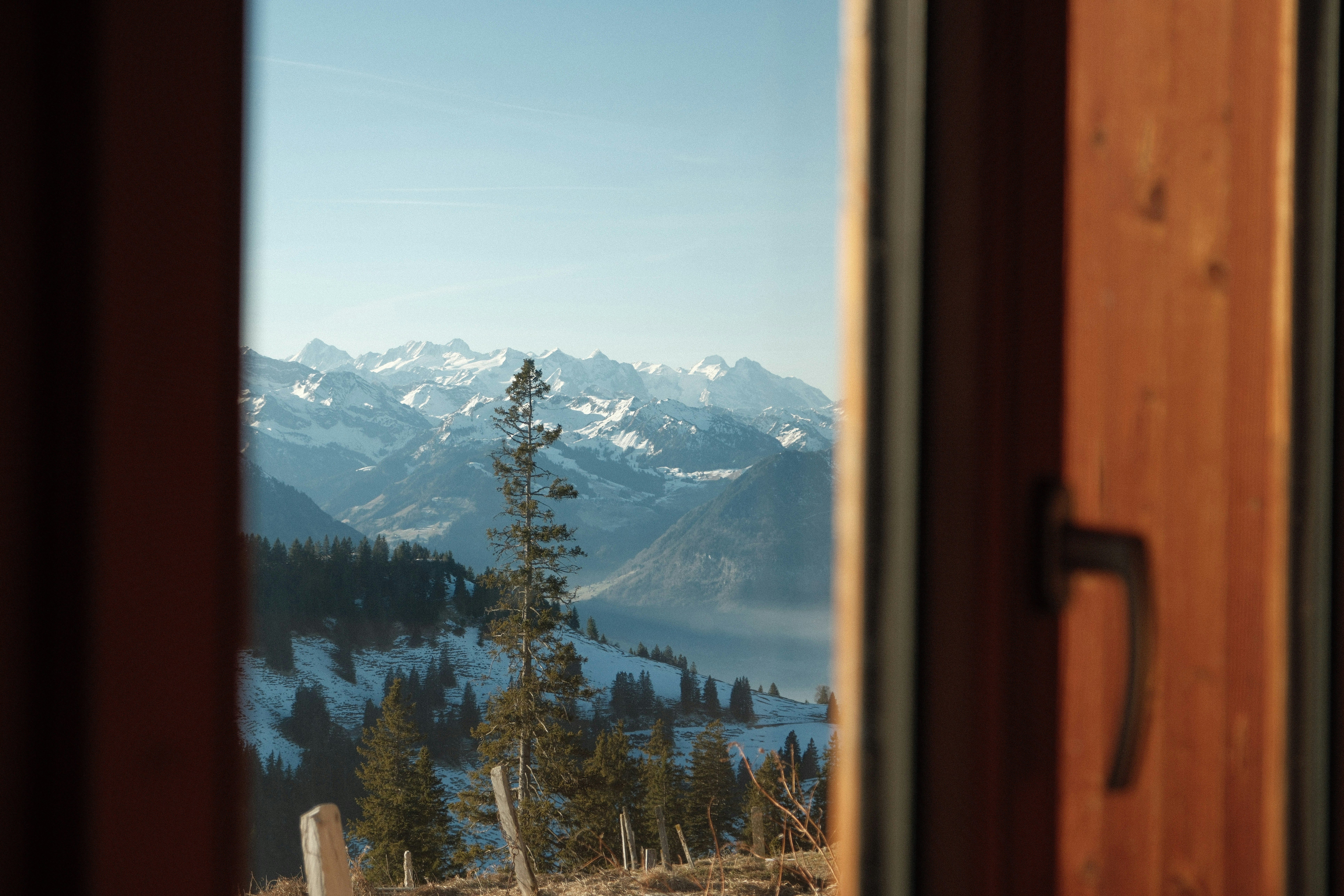 Snowy mountain range seen through a wooden window