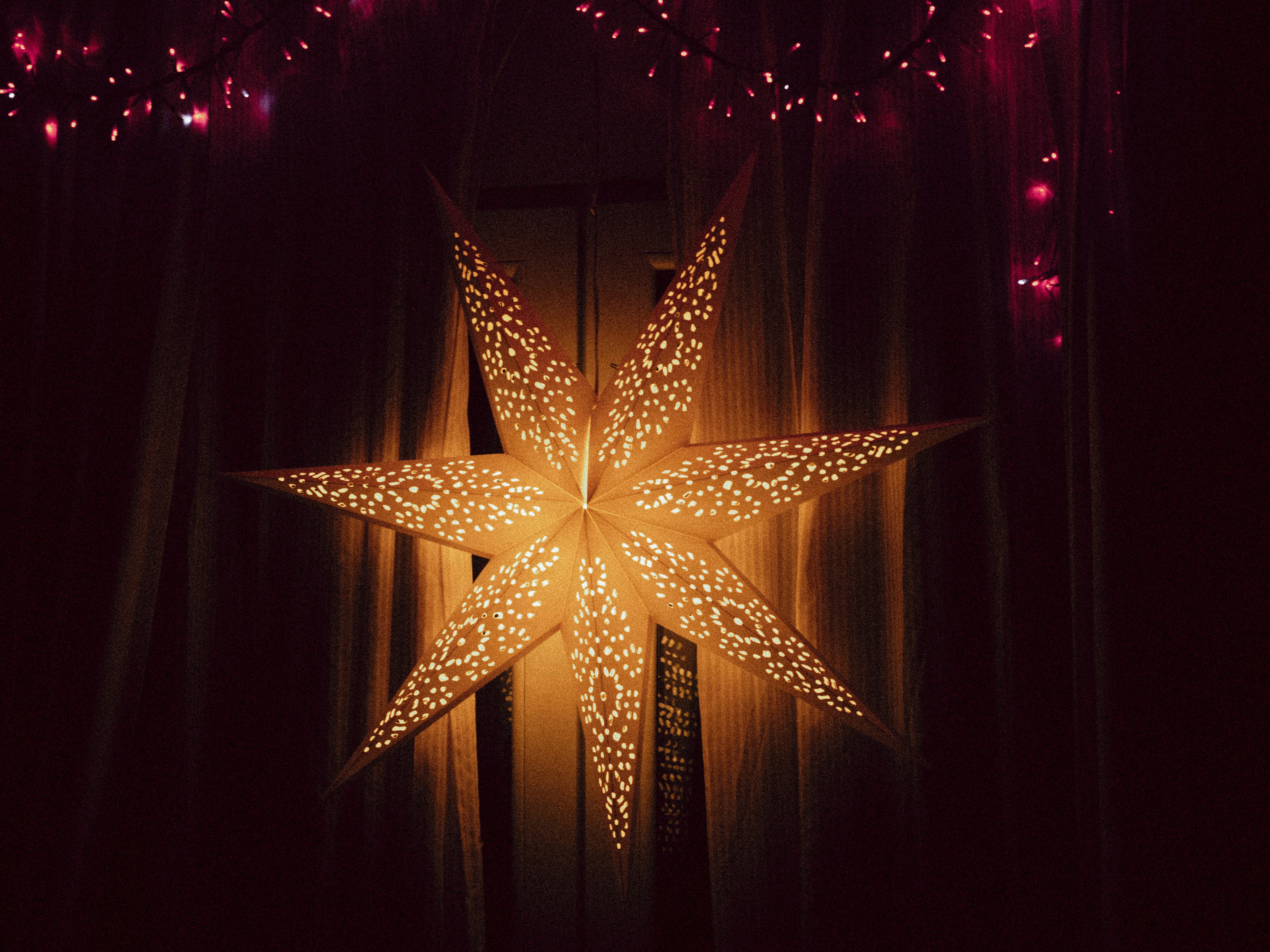 A glowing star lantern hangs against dark curtains