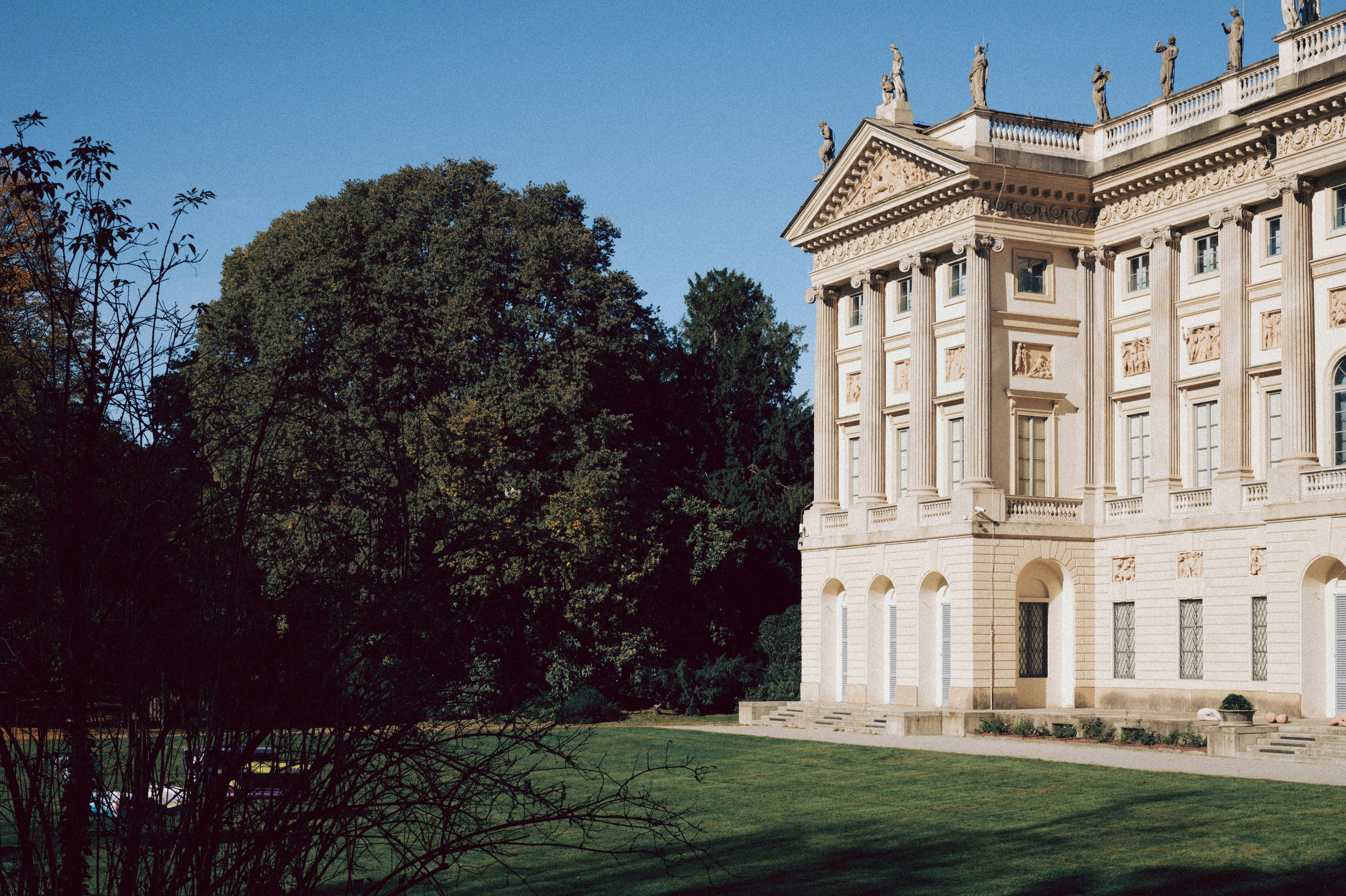 Großes klassizistisches Gebäude mit gepflegtem Rasen und Bäumen