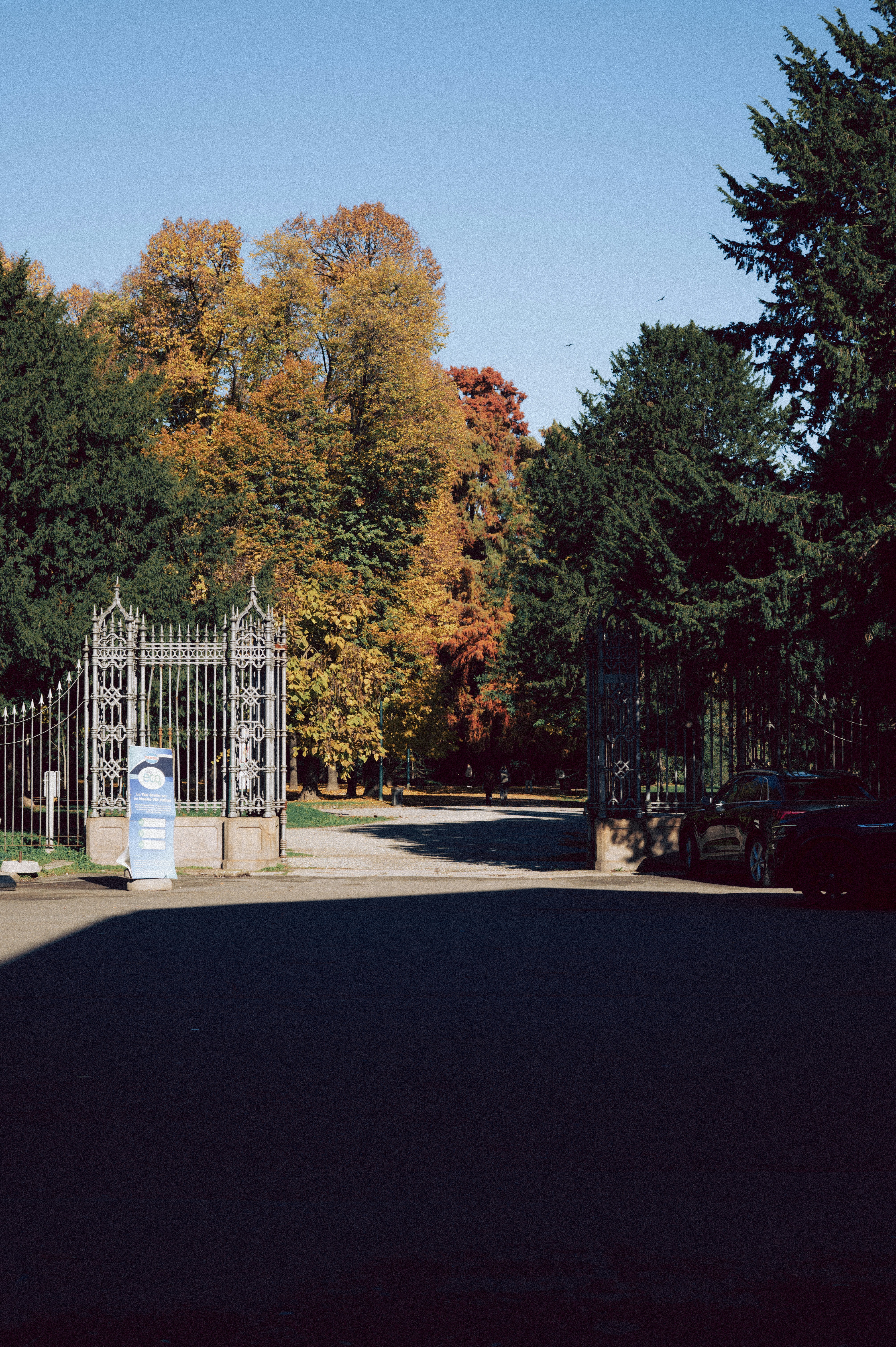 Verzierte Tore öffnen sich zu einem Park mit Herbstbäumen.