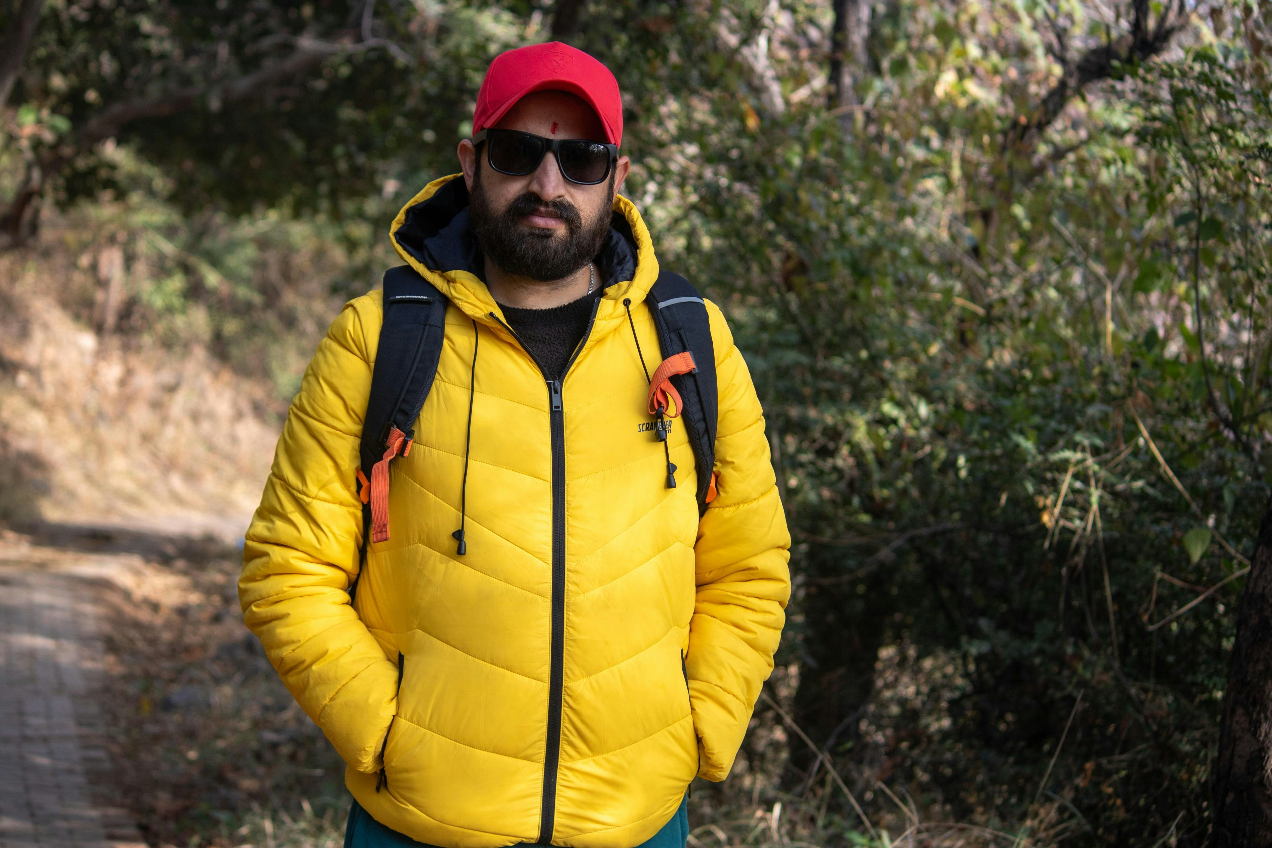 Man wearing a yellow jacket and red cap outdoors