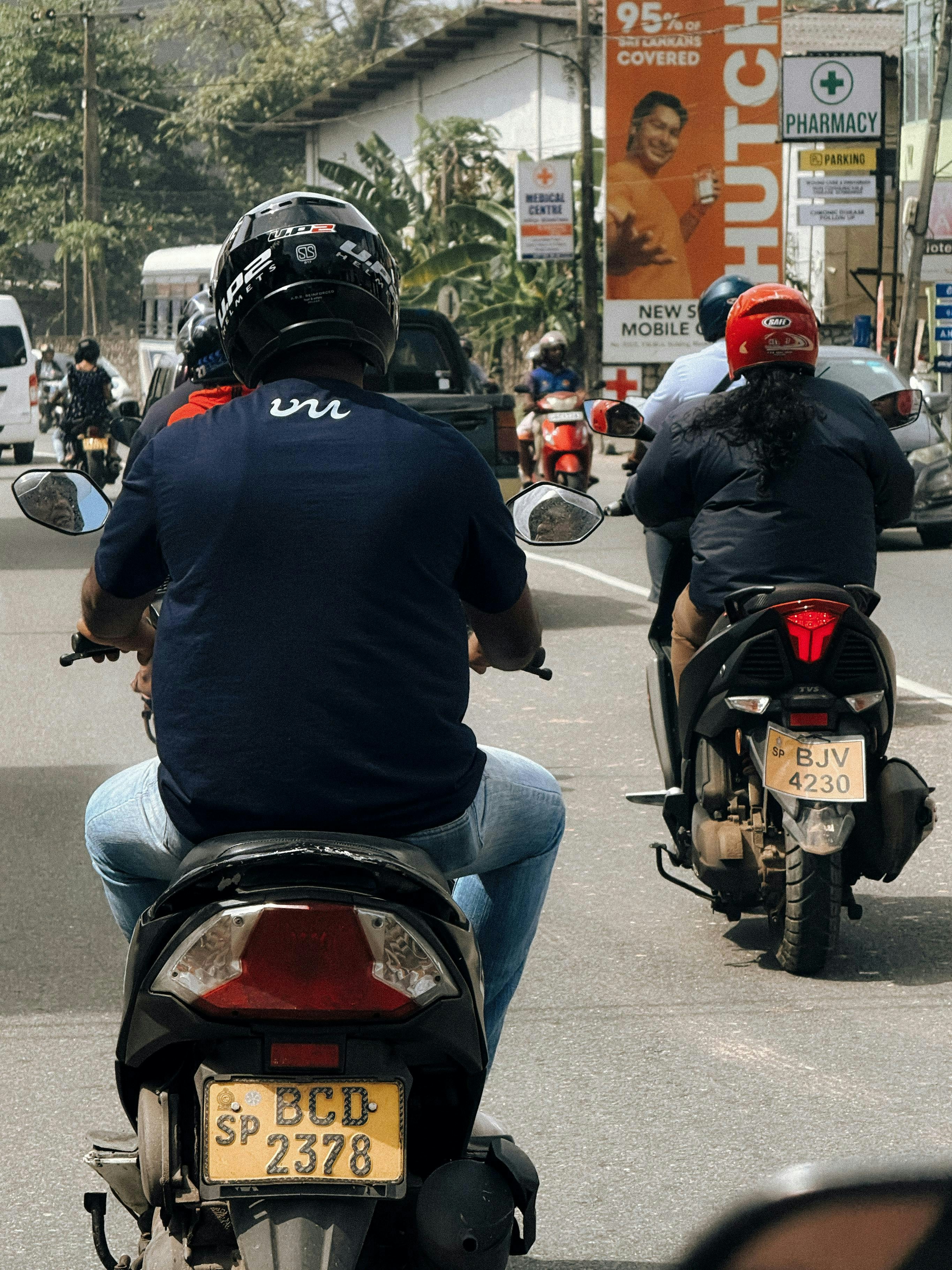 People riding scooters on a busy street.
