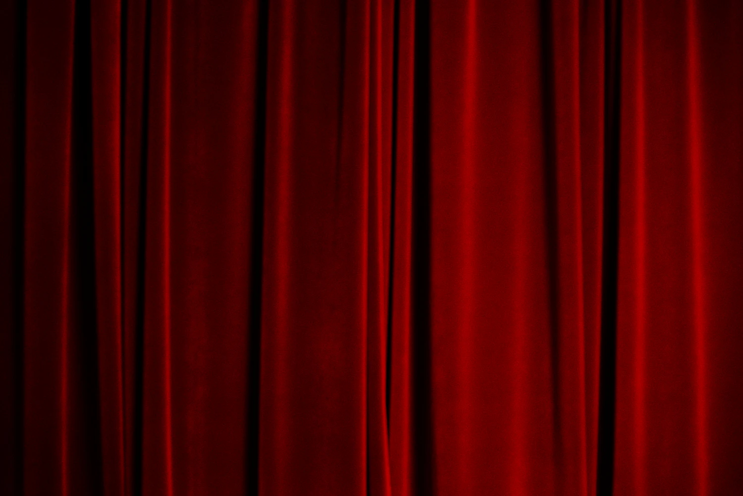 Closed red velvet stage curtains lit from below