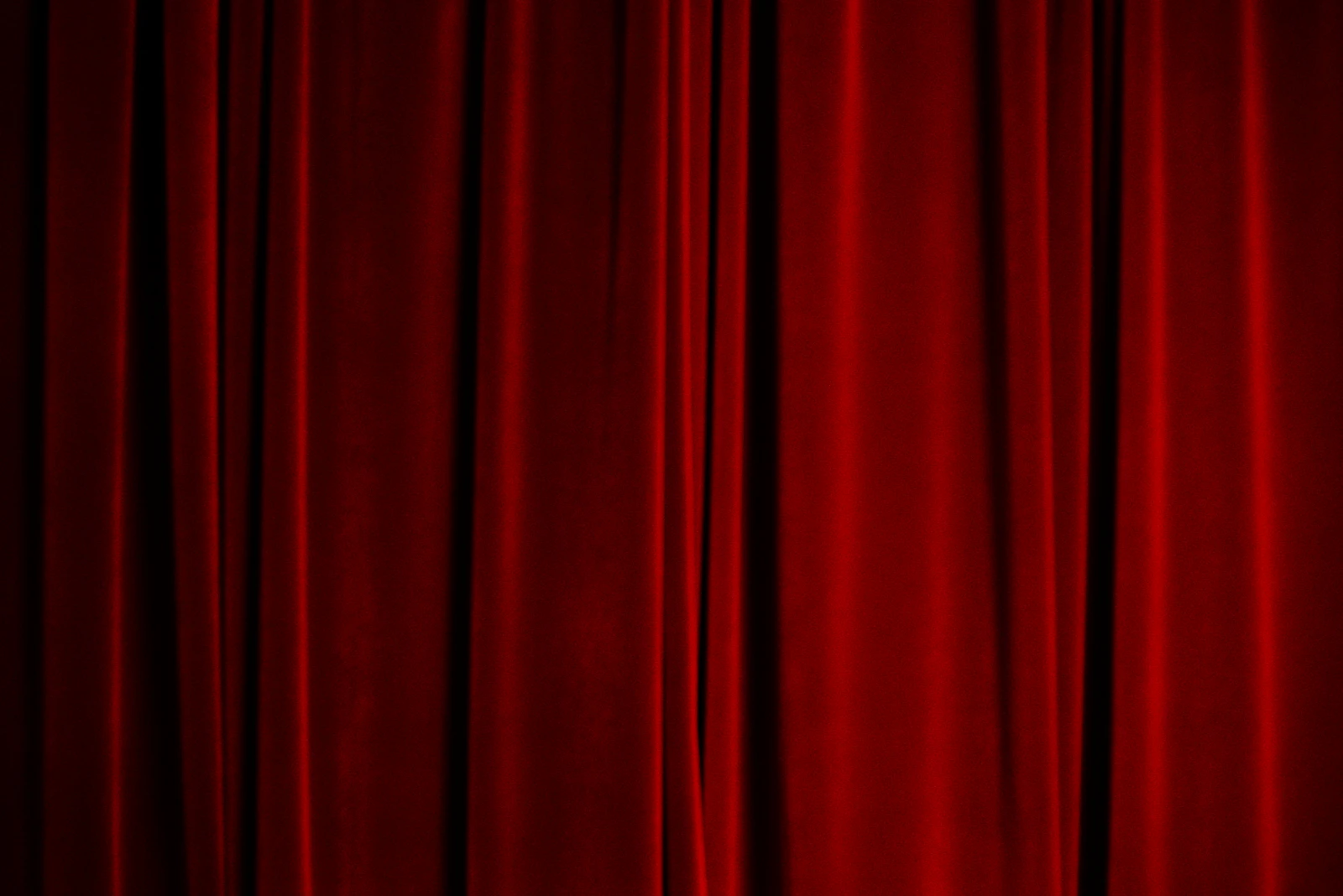 Rote Samt-Theatervorhänge auf einer dunklen Bühne, geschlossen vor der Aufführung