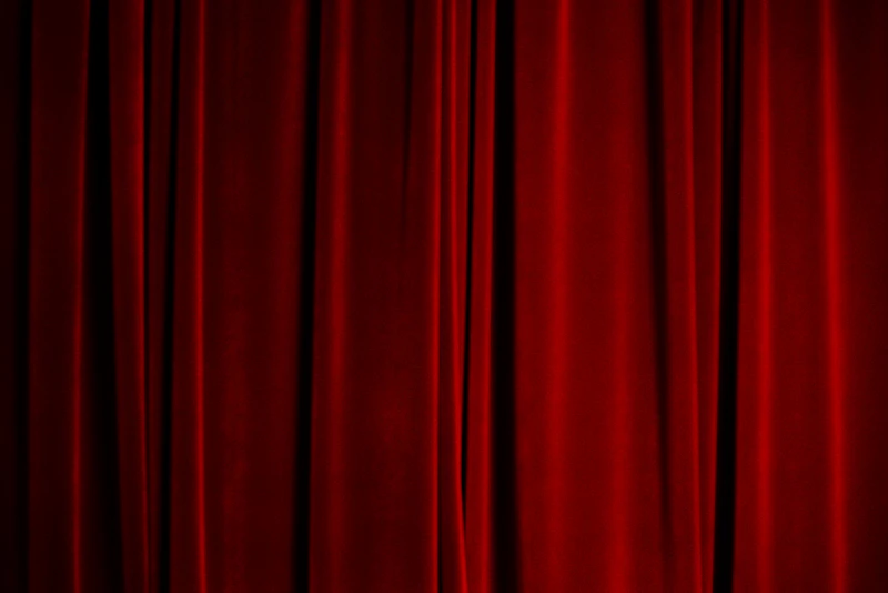 Rote Samt-Theatervorhänge auf einer dunklen Bühne, geschlossen vor der Aufführung