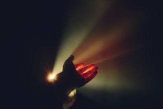 Hand reaching towards bright light beams