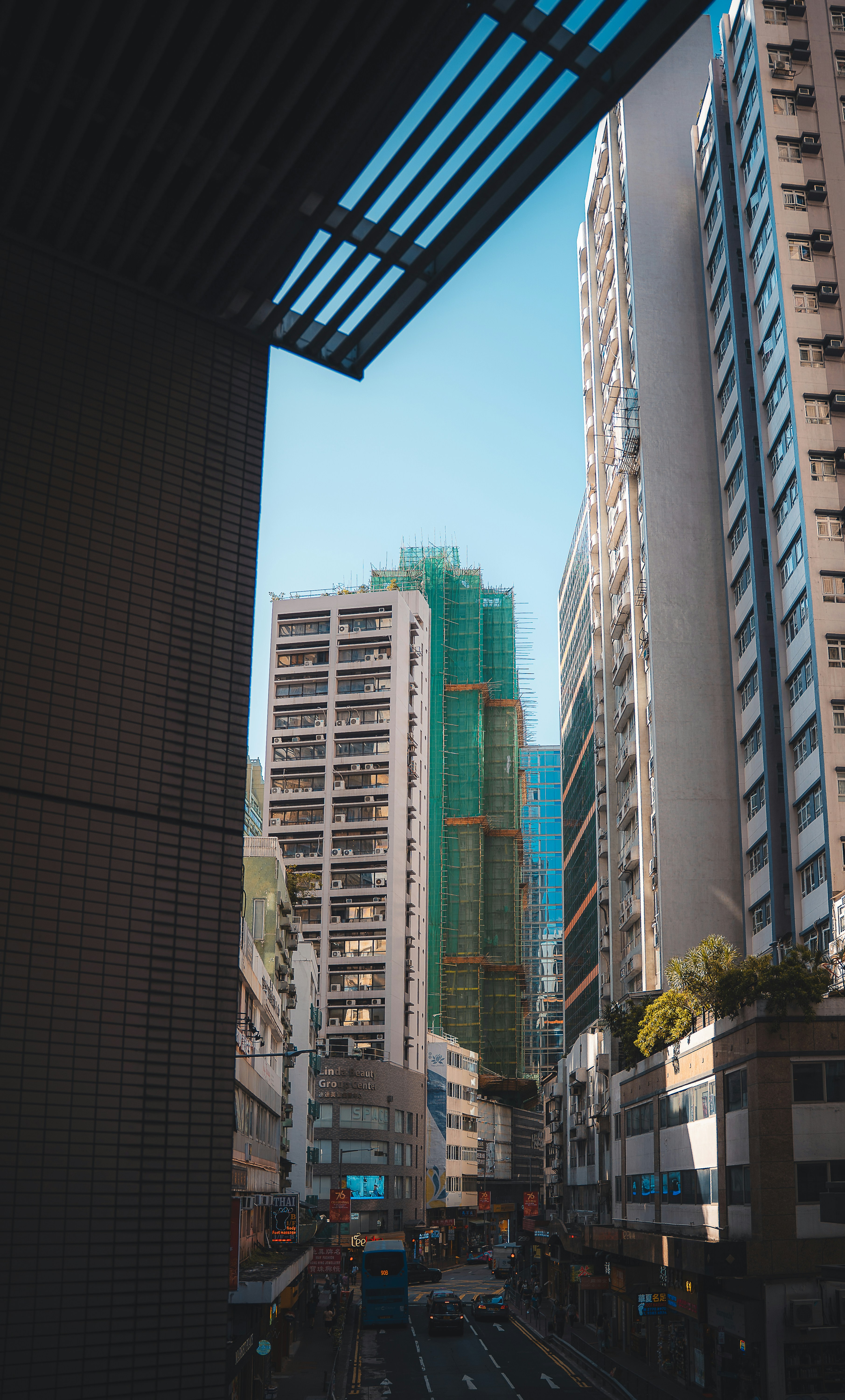 Tall buildings line a street with cars and blue sky.
