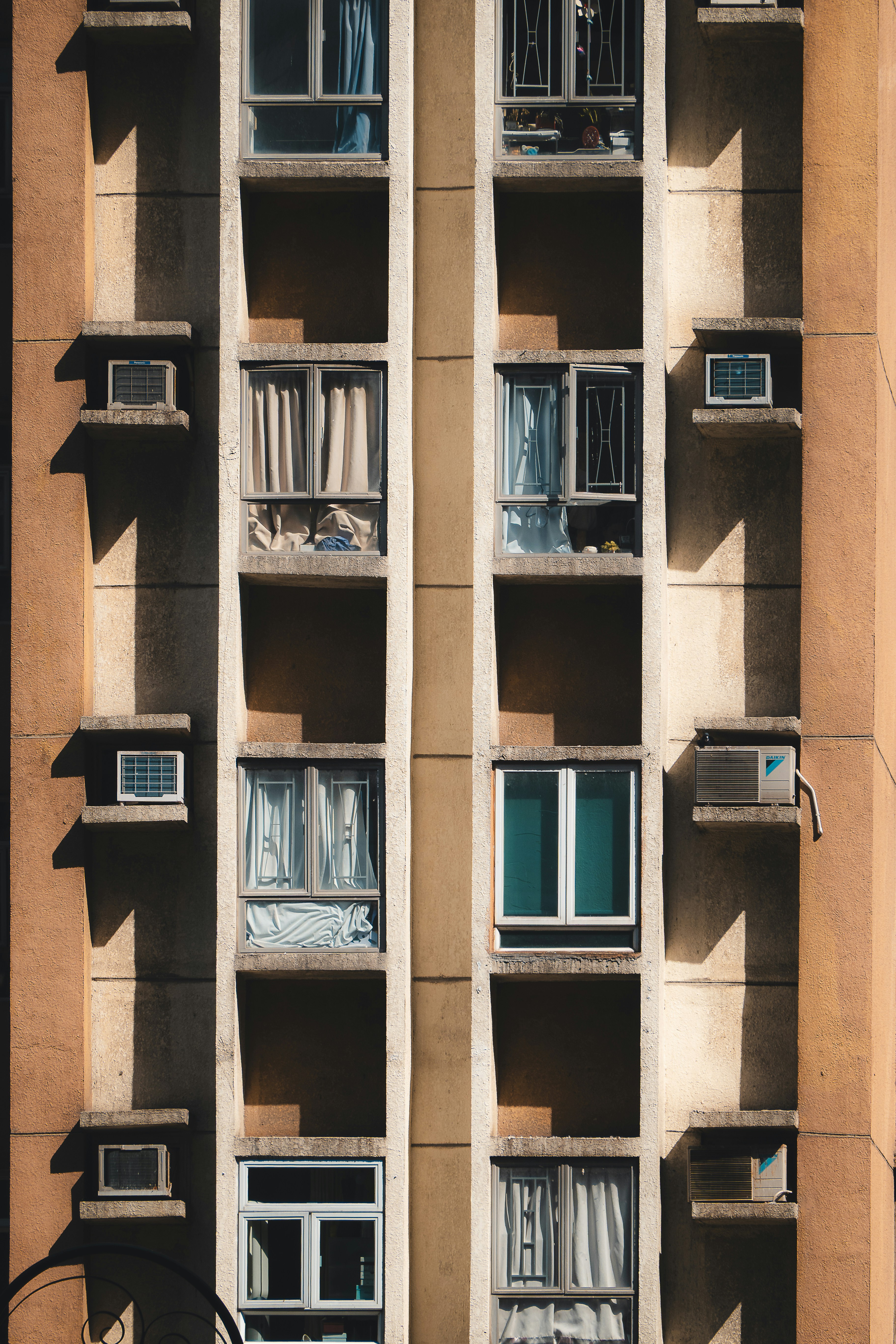 Apartment building facade with many windows and air conditioners.