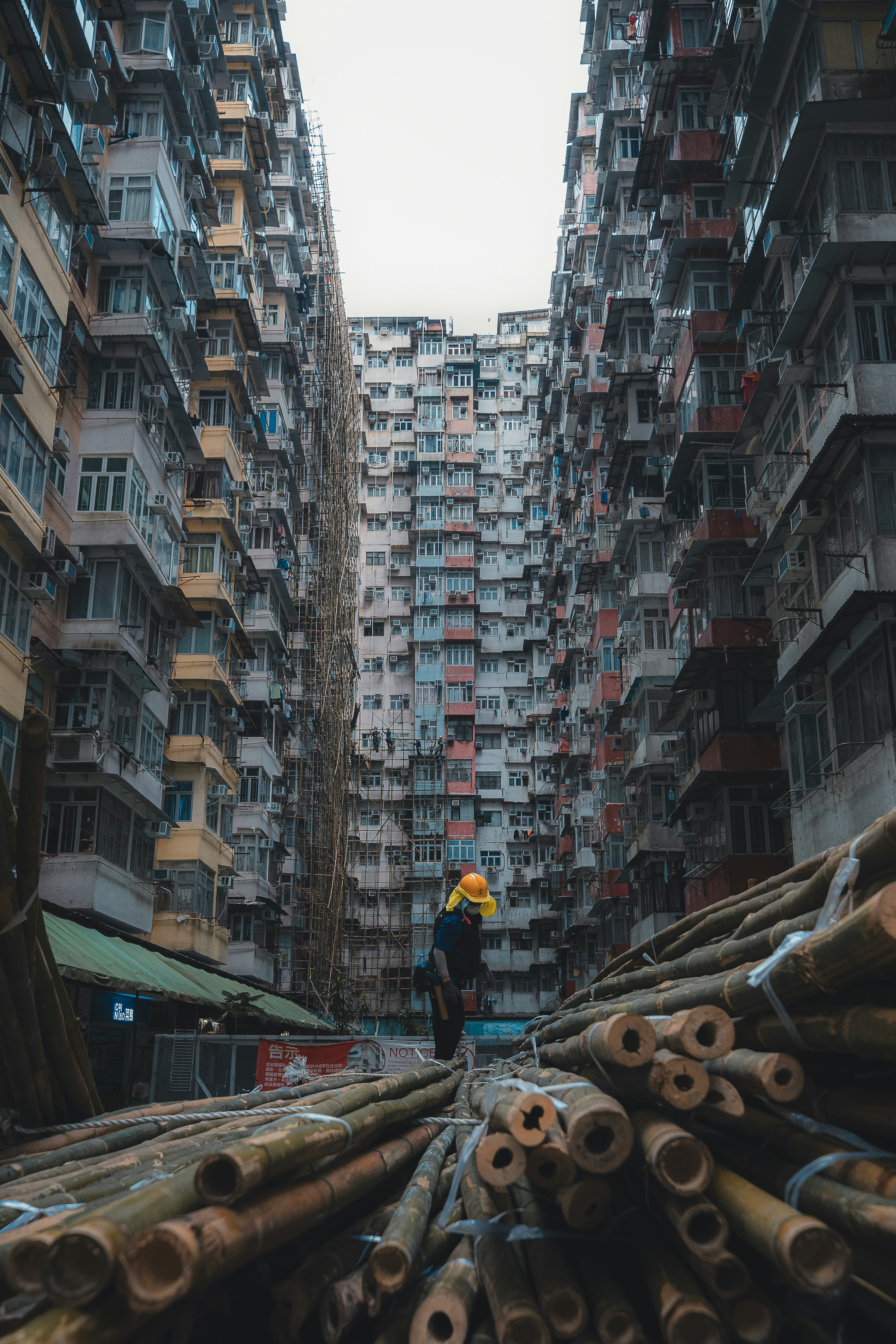 Man in yellow hard hat amidst dense apartment buildings