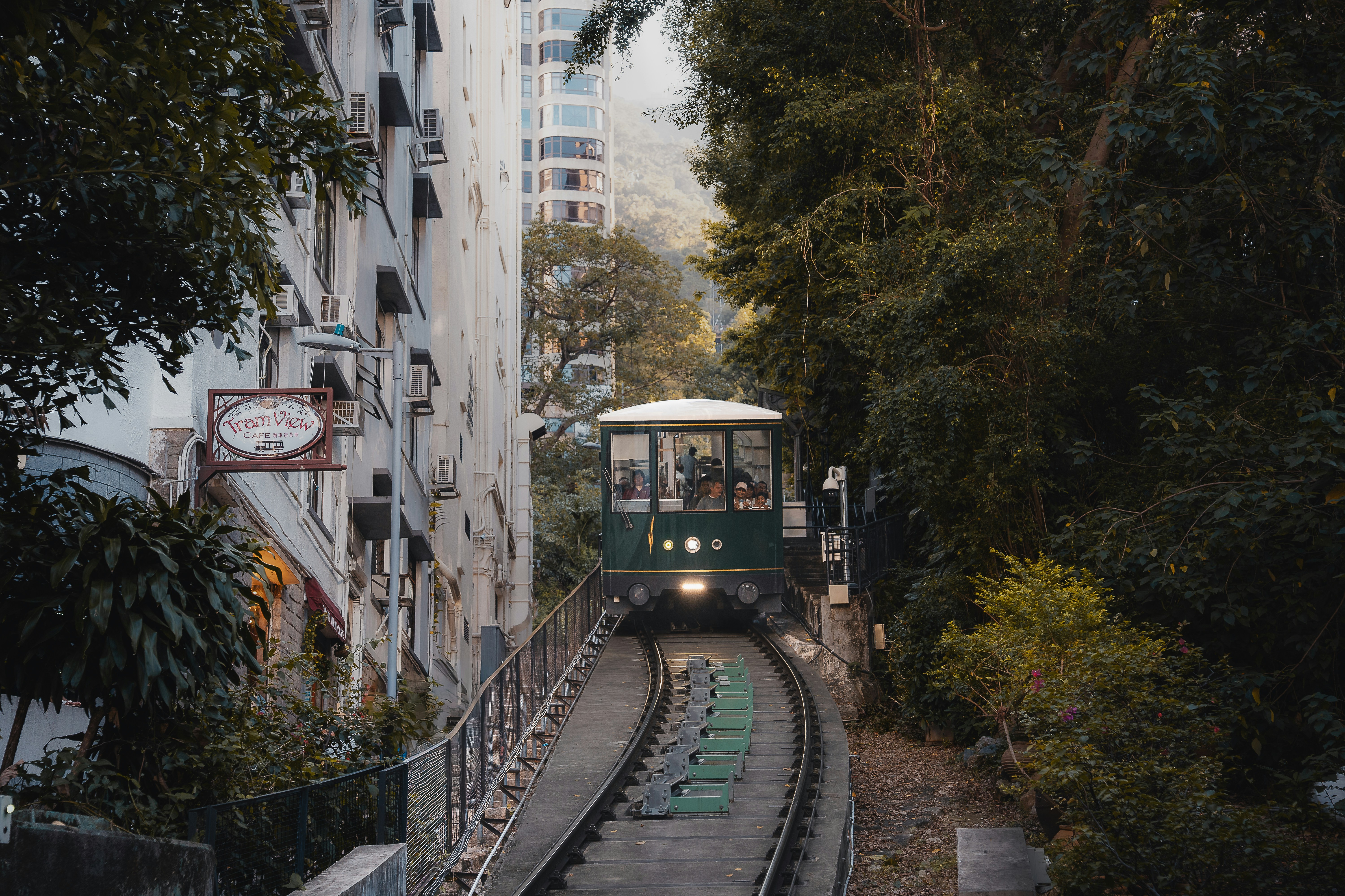 Funicular train traveling uphill between buildings and trees.