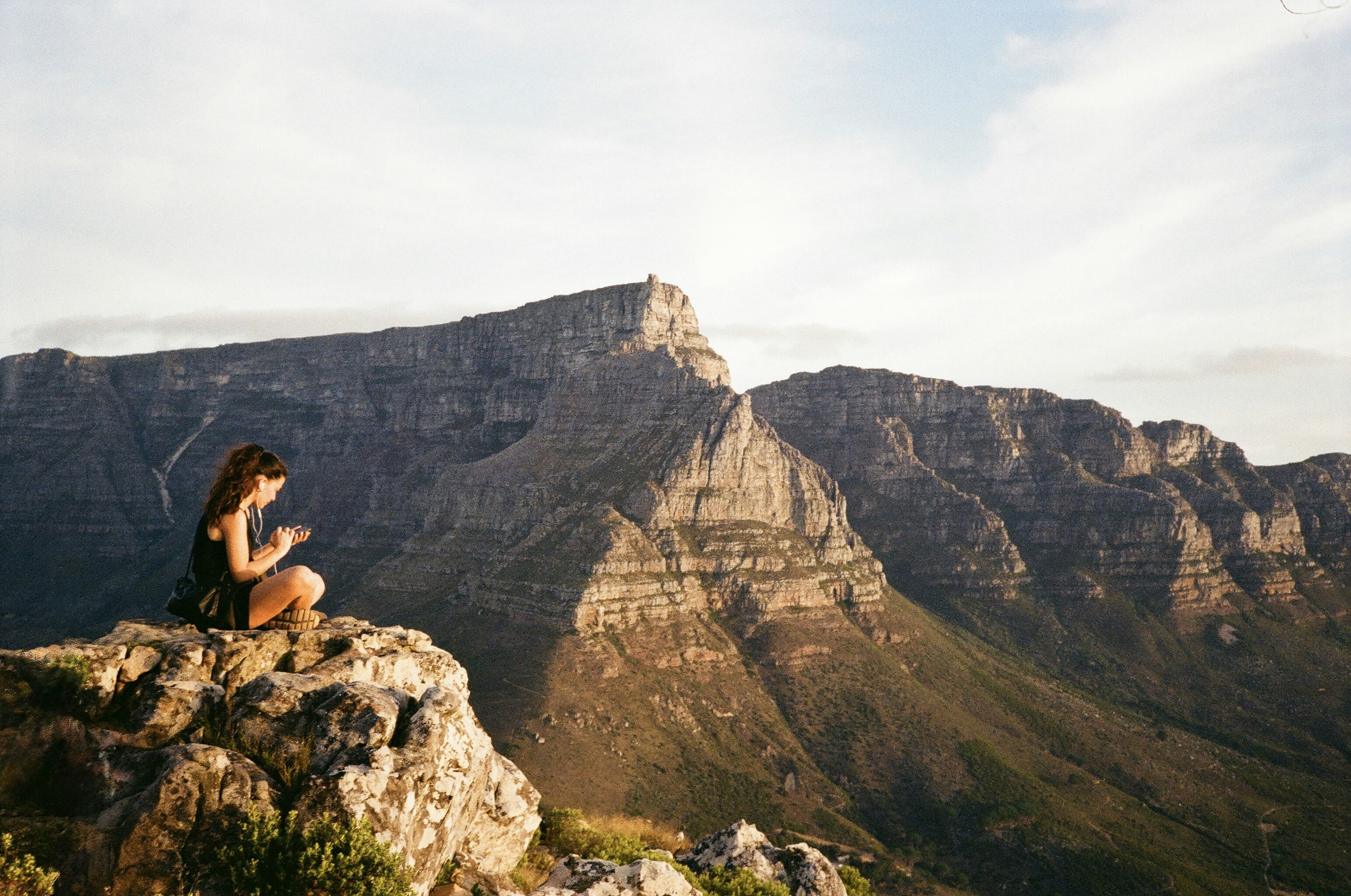 Woman sitting on rocky cliff overlooking mountains