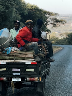 Three people ride in the back of a truck.