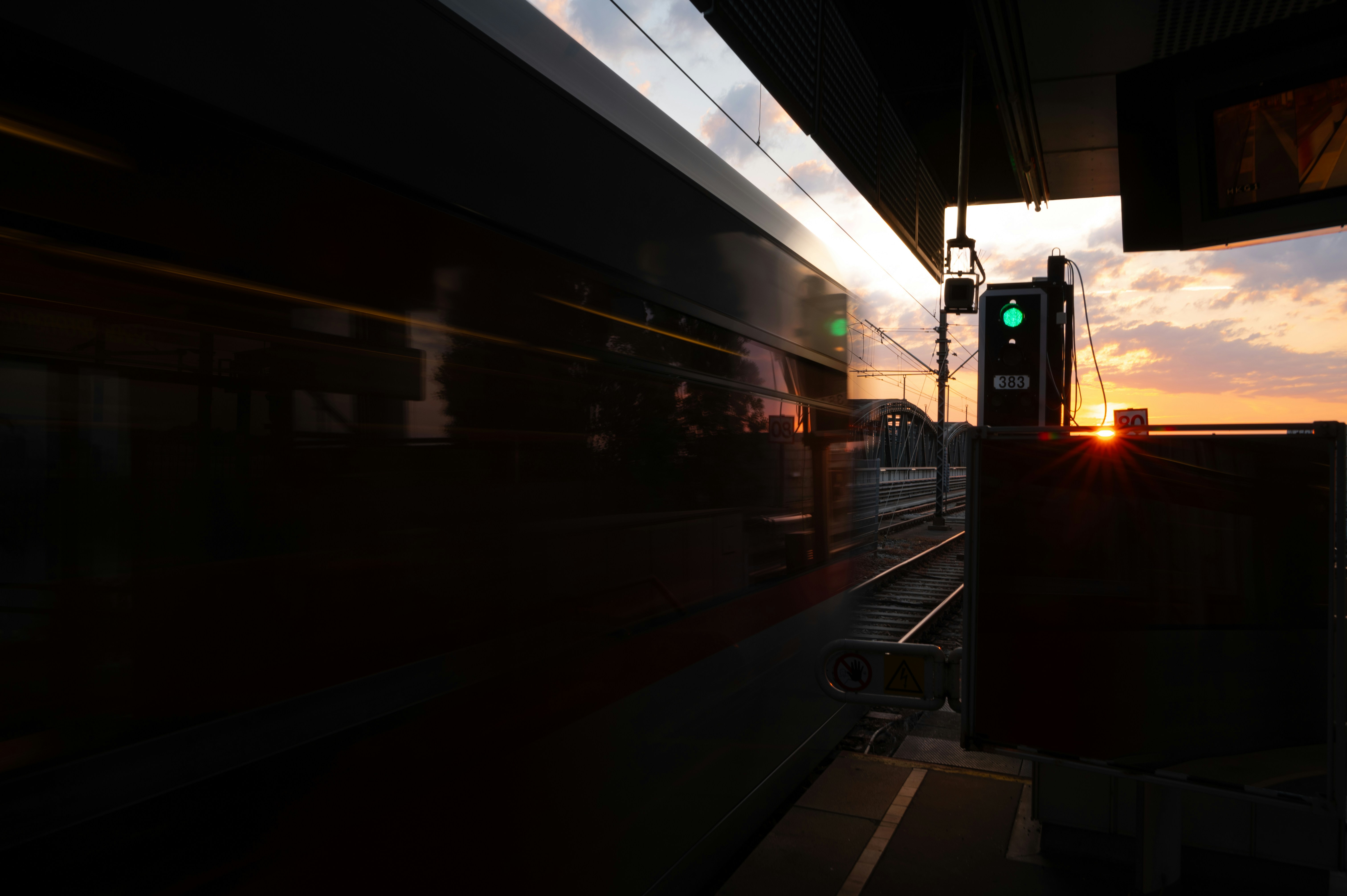 Train moving past station at sunset