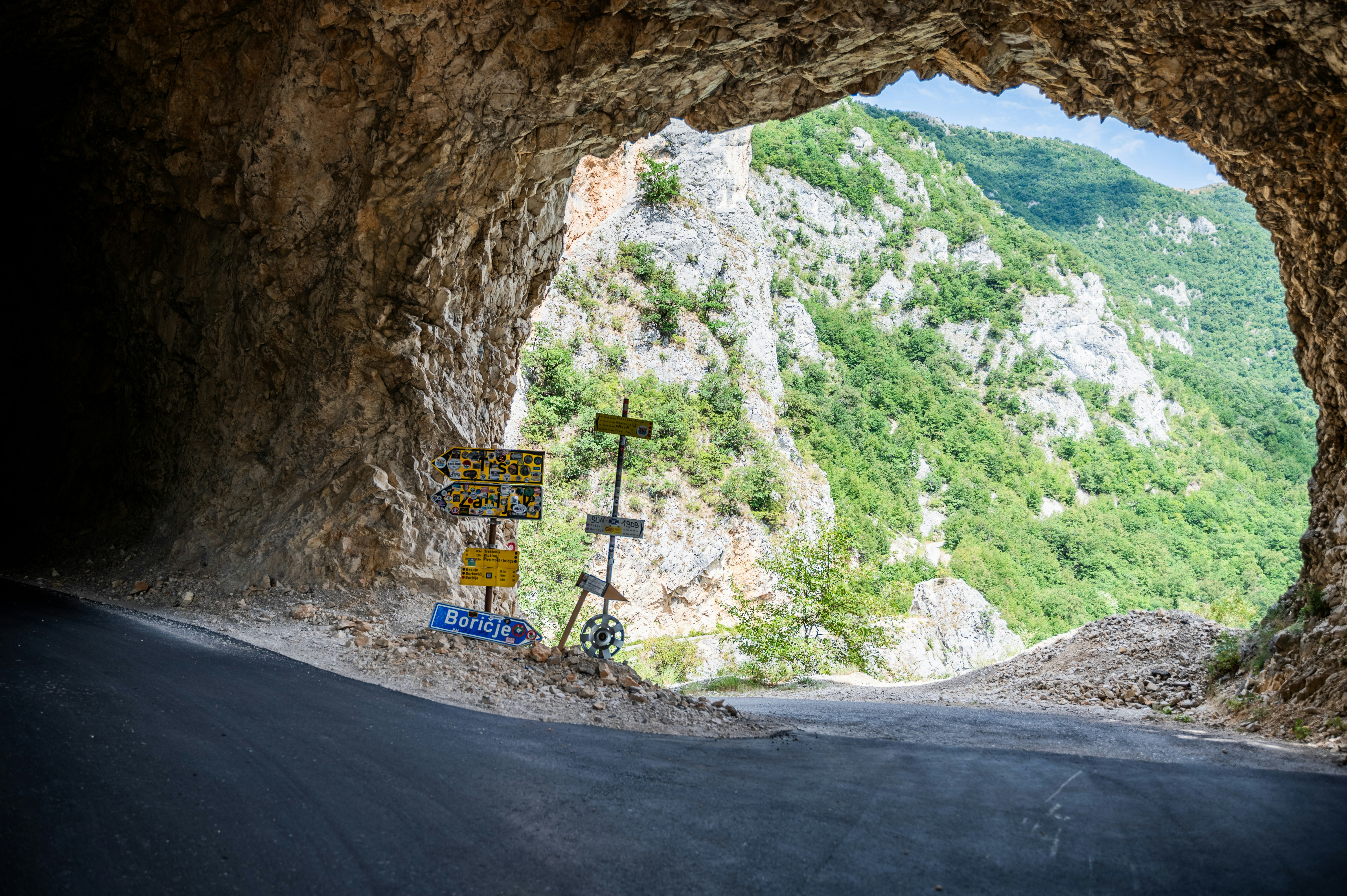 View from a cave exit to a green mountain landscape.