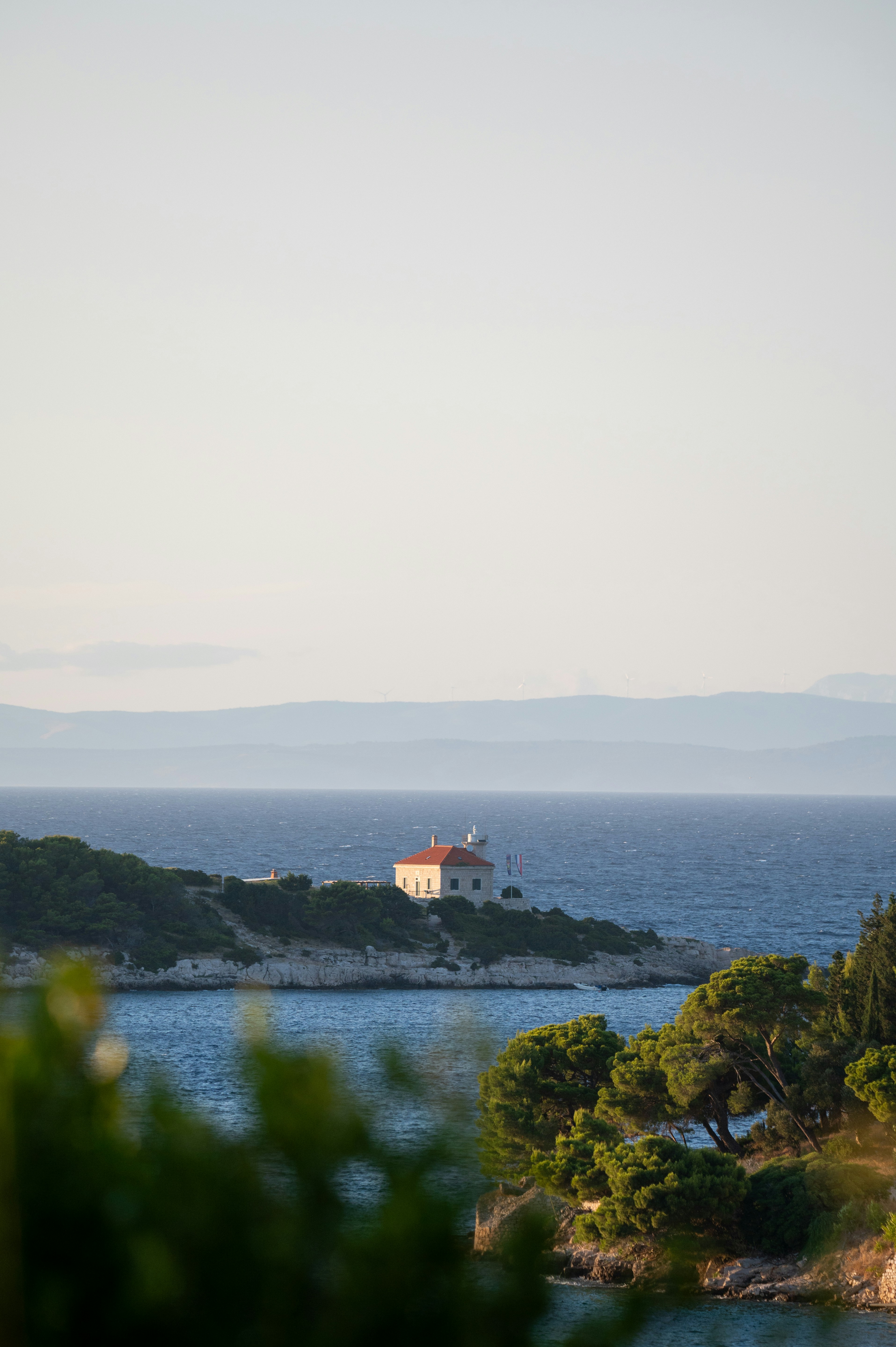 Lighthouse on a coastal island with green trees.