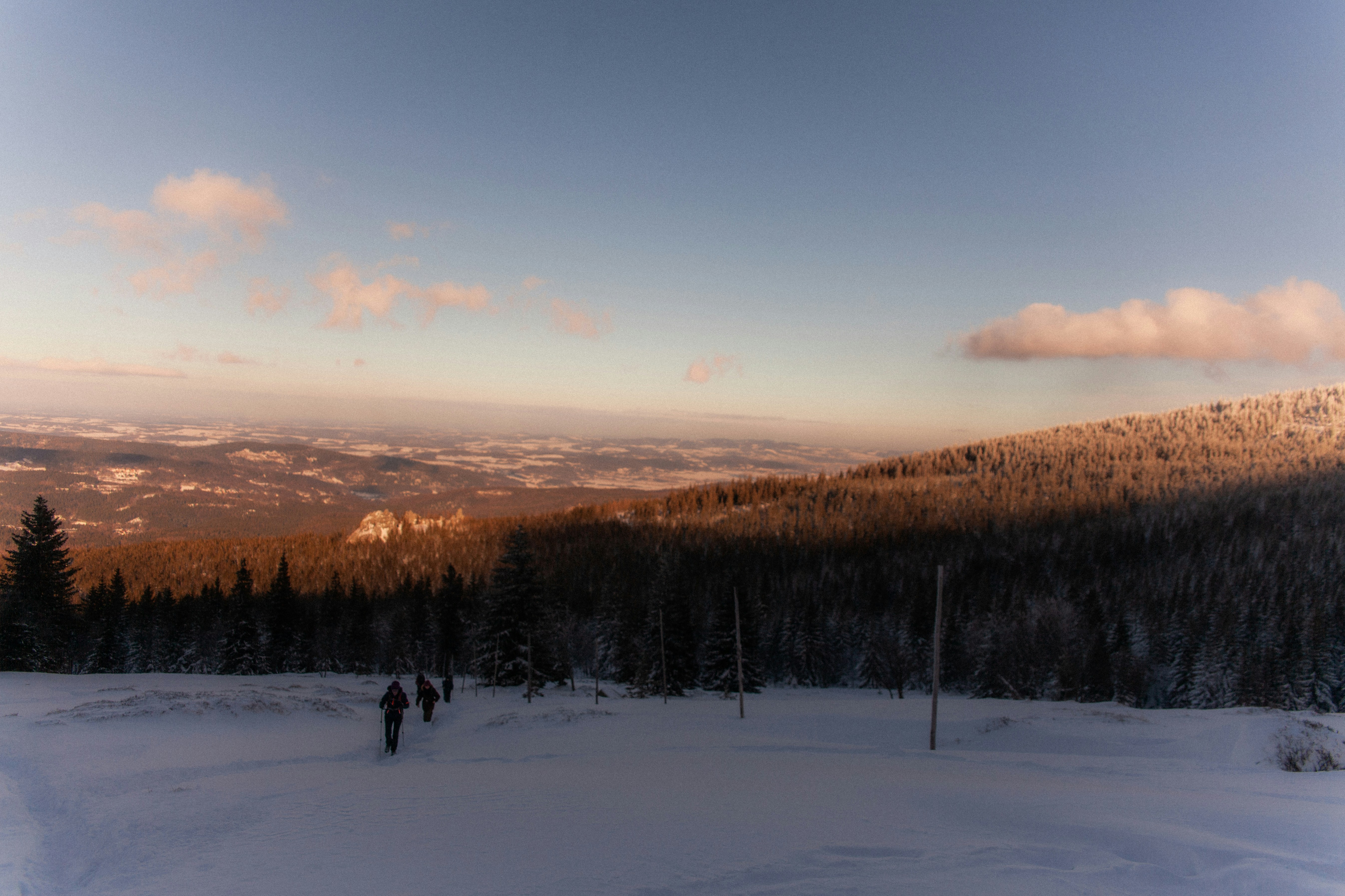 Hikers walking on snowy mountain trail at sunset