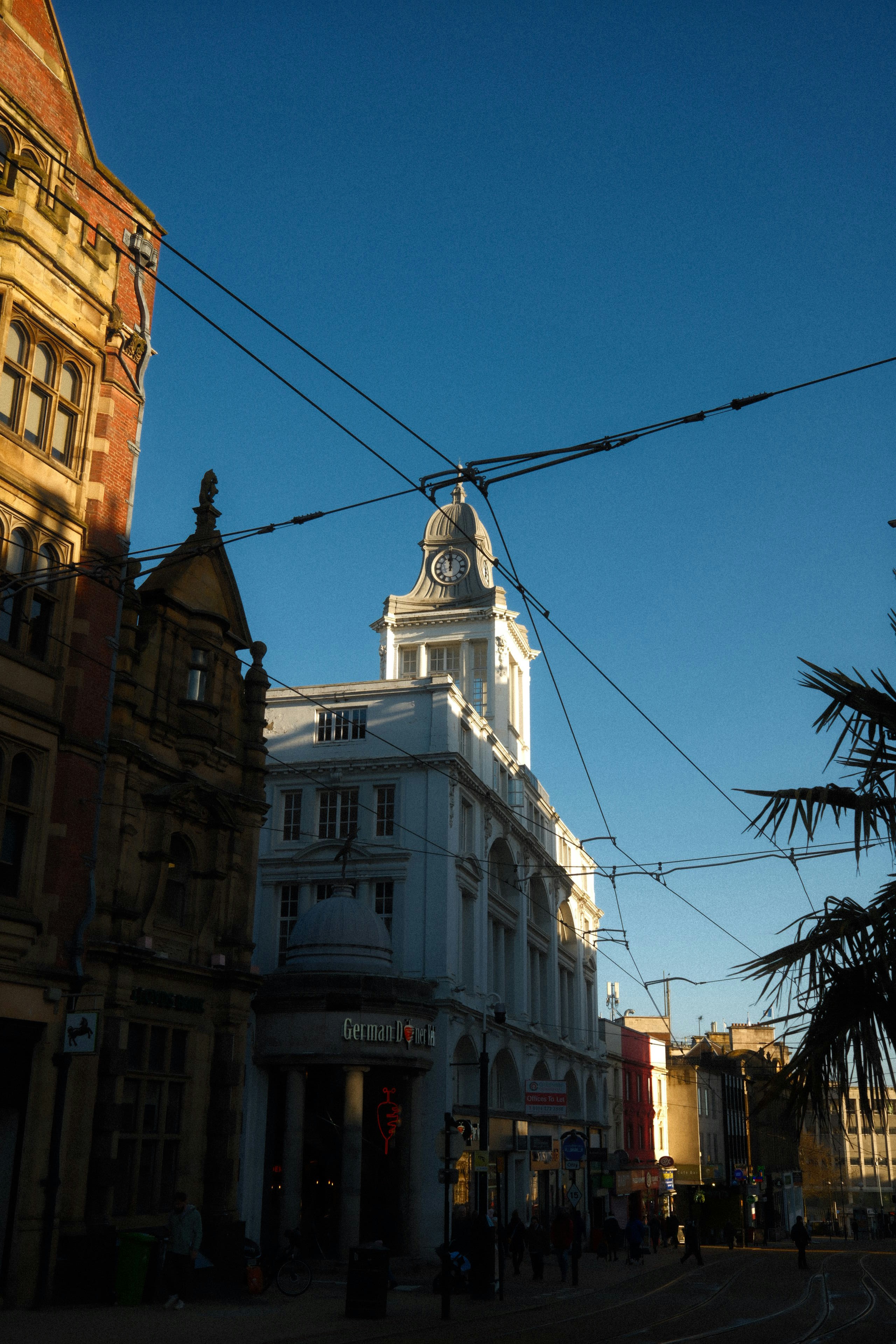 Buildings and overhead wires against a clear blue sky.