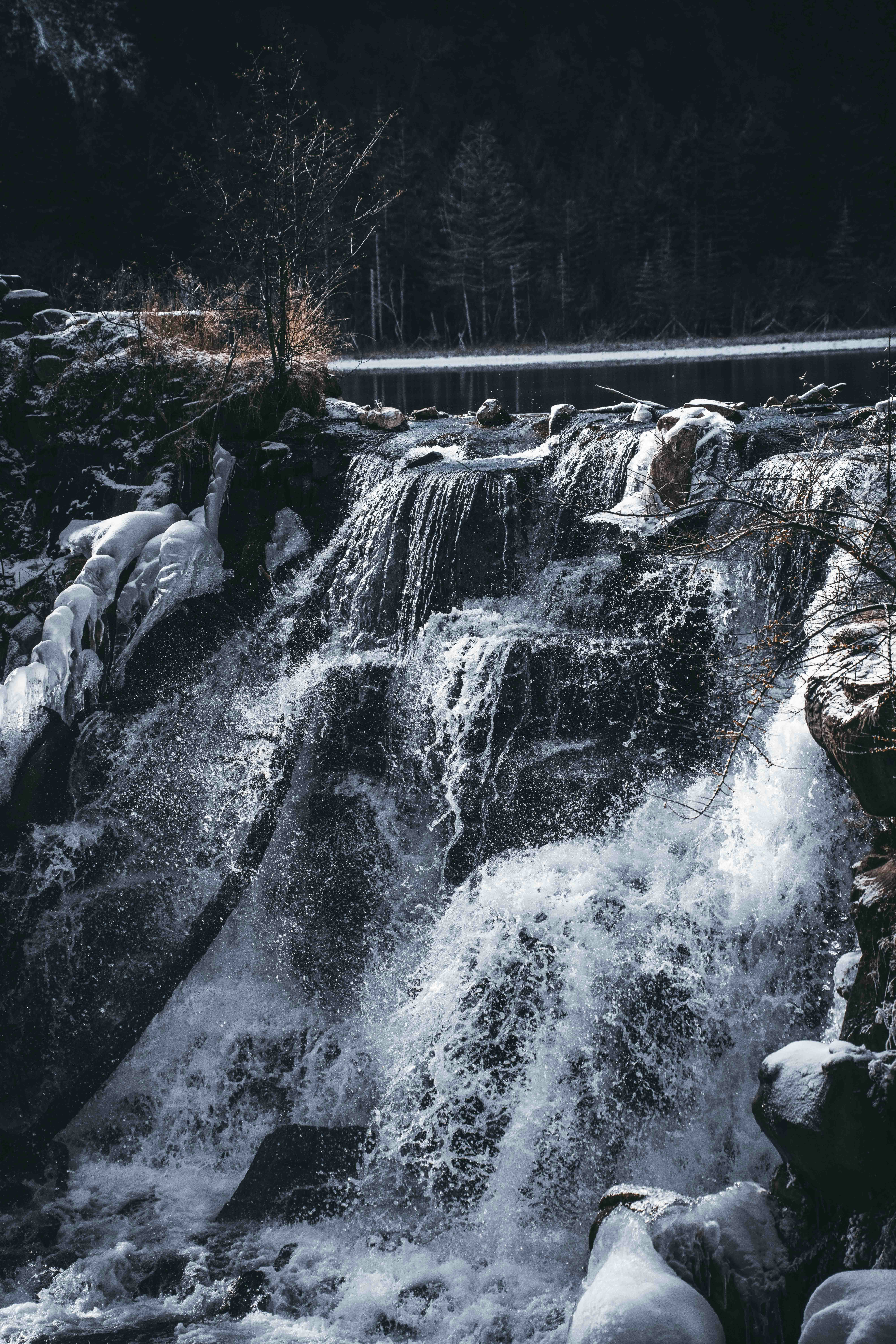 A powerful waterfall cascades over rocks in a winter forest.