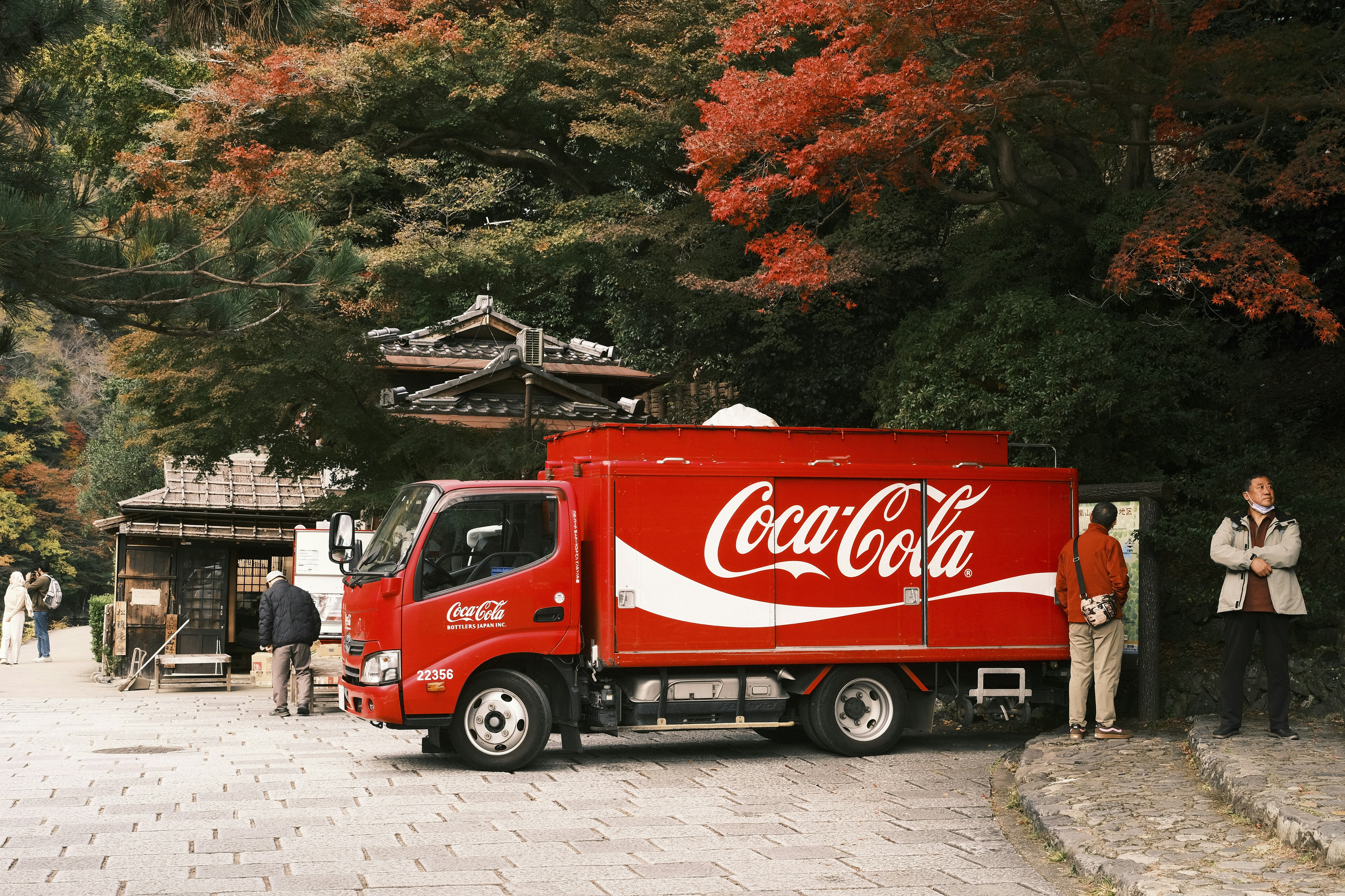 A red coca-cola truck parked near trees.
