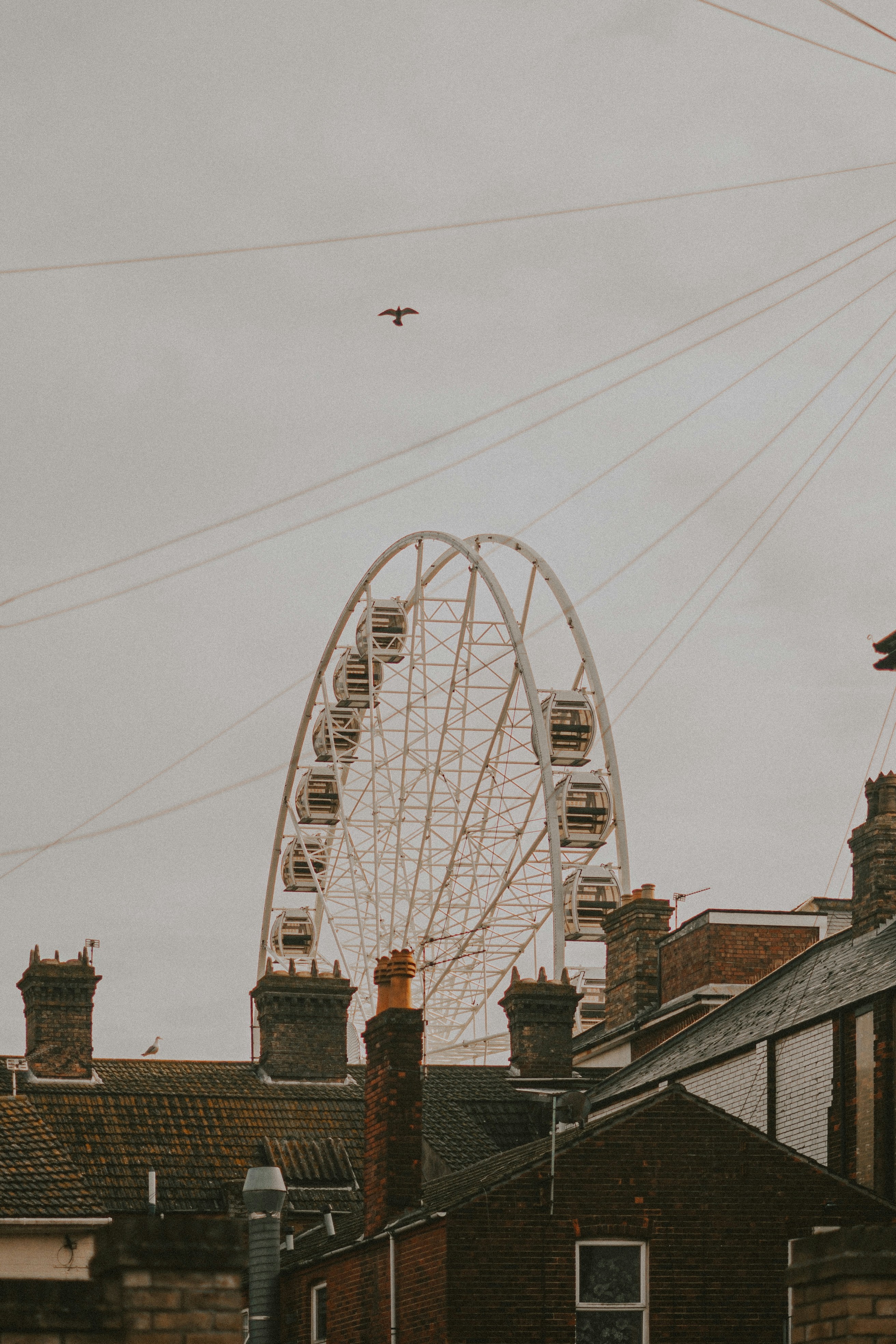 Riesenrad hinter Dächern unter bewölktem Himmel