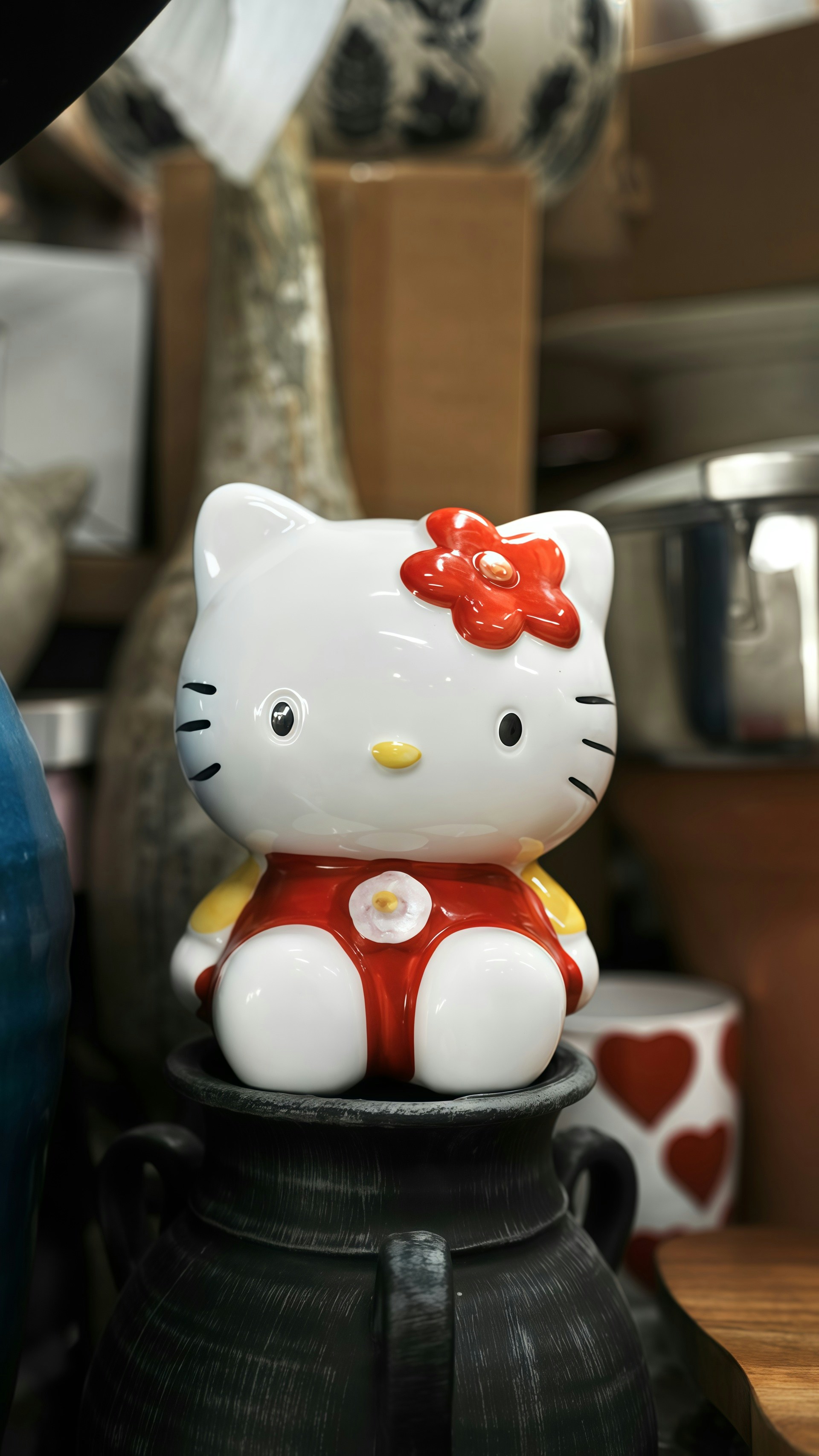 A hello kitty figurine sits on a dark vase.