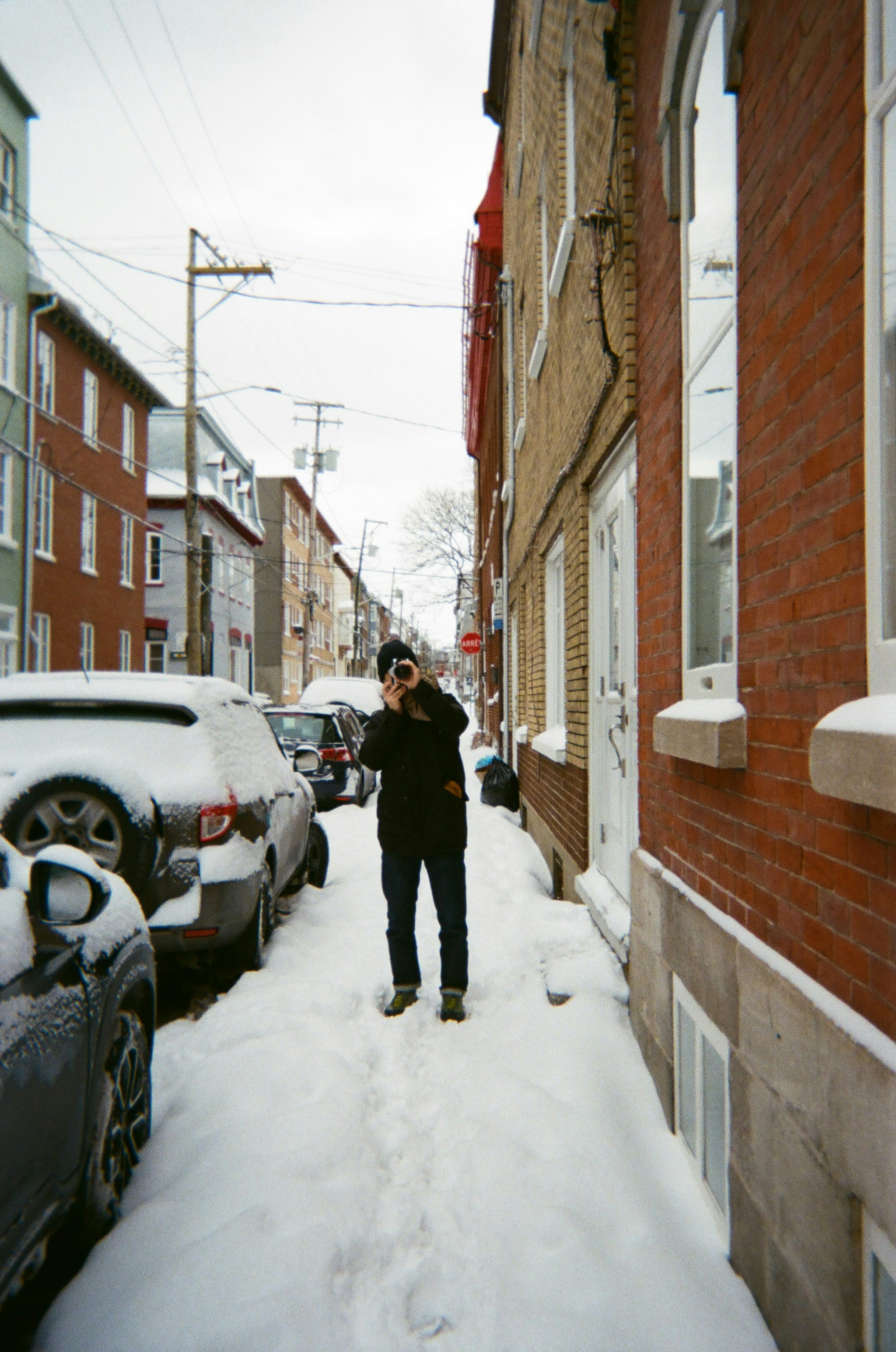 Person taking a photo on a snowy street.