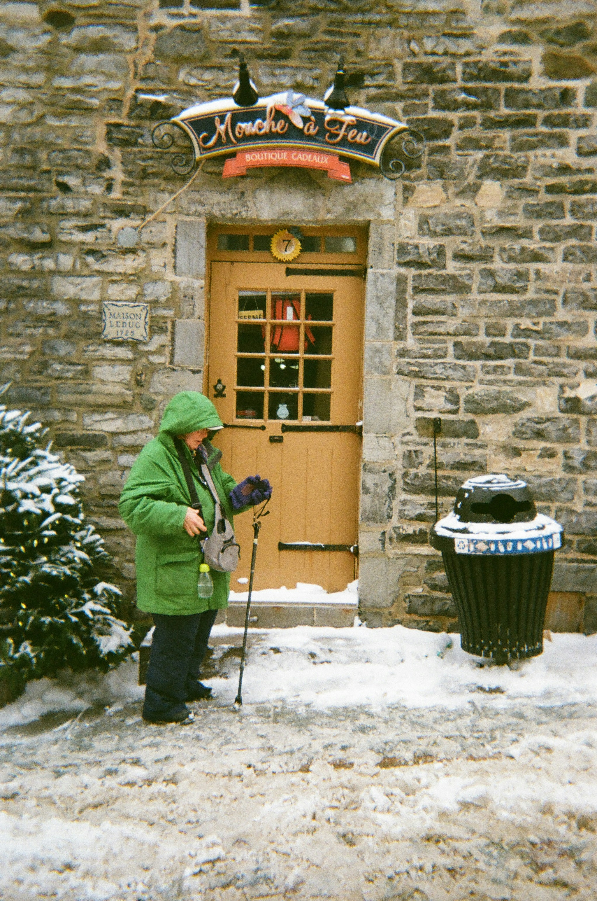 Woman in green coat stands by a stone building