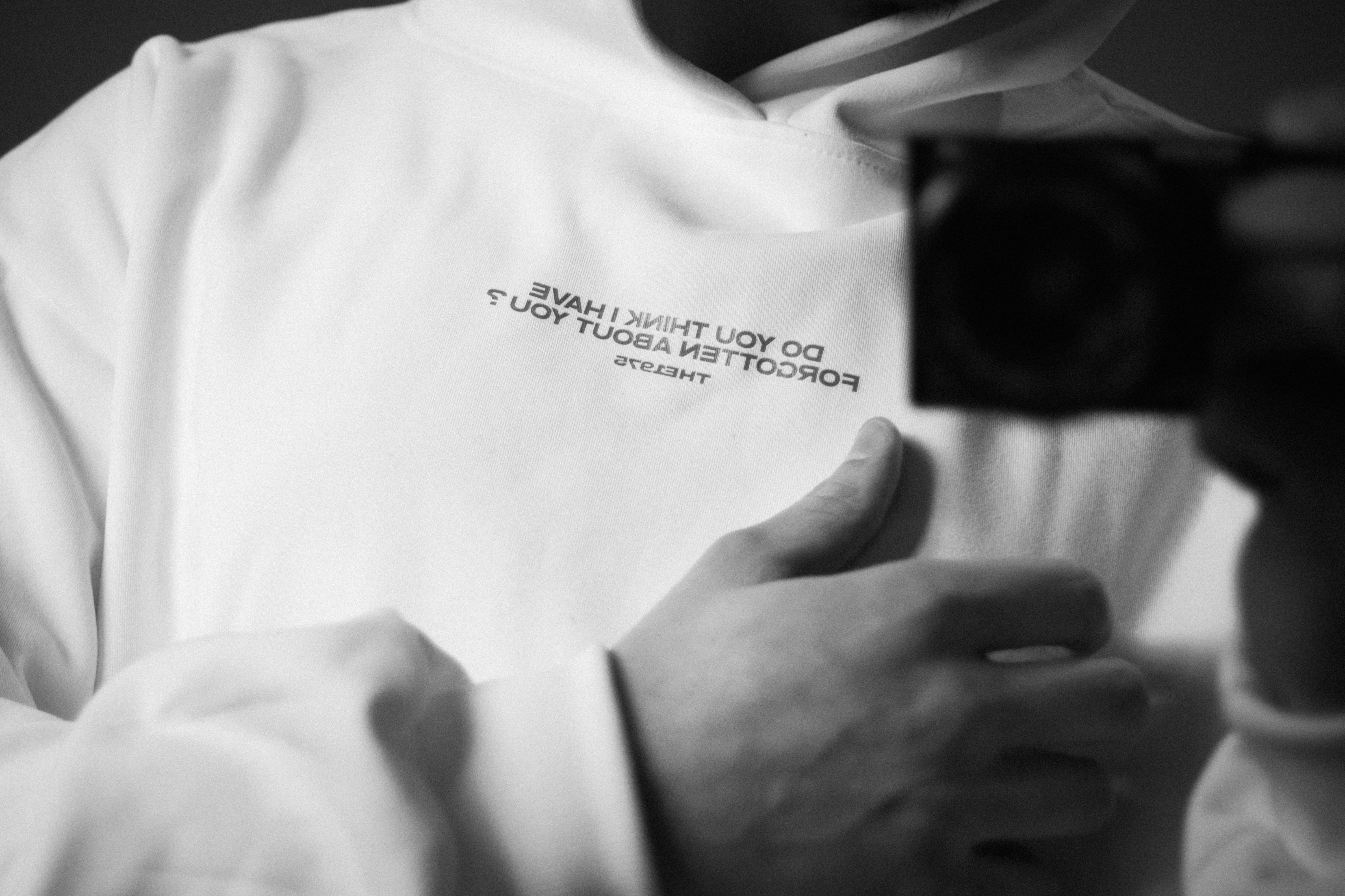 Person in white sweatshirt holding a camera.