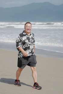Smiling man walks on a sandy Wollongong beach healthy lifestyle and massage