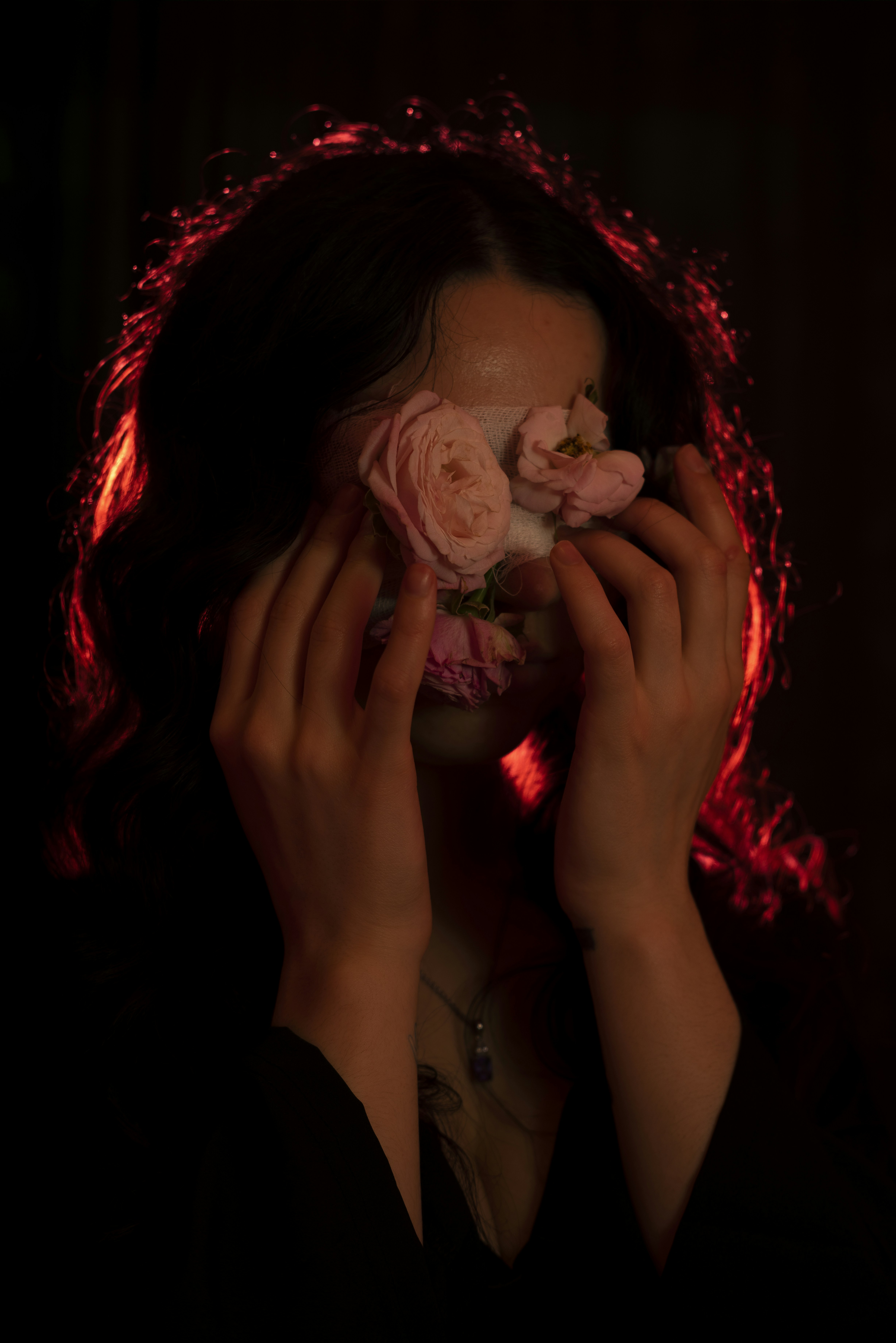 Woman holding pink roses over her face