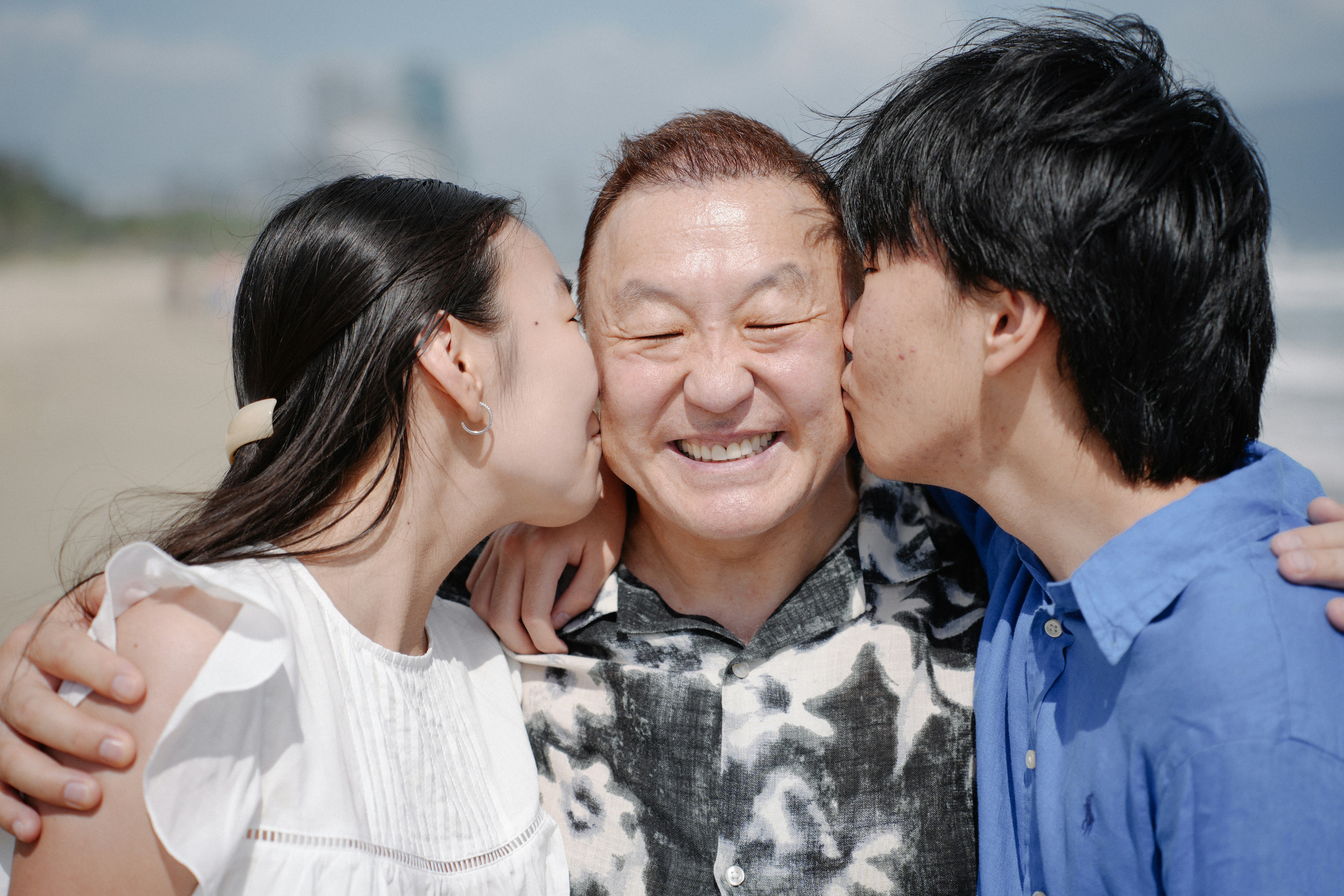 Two people kissing a man on the beach