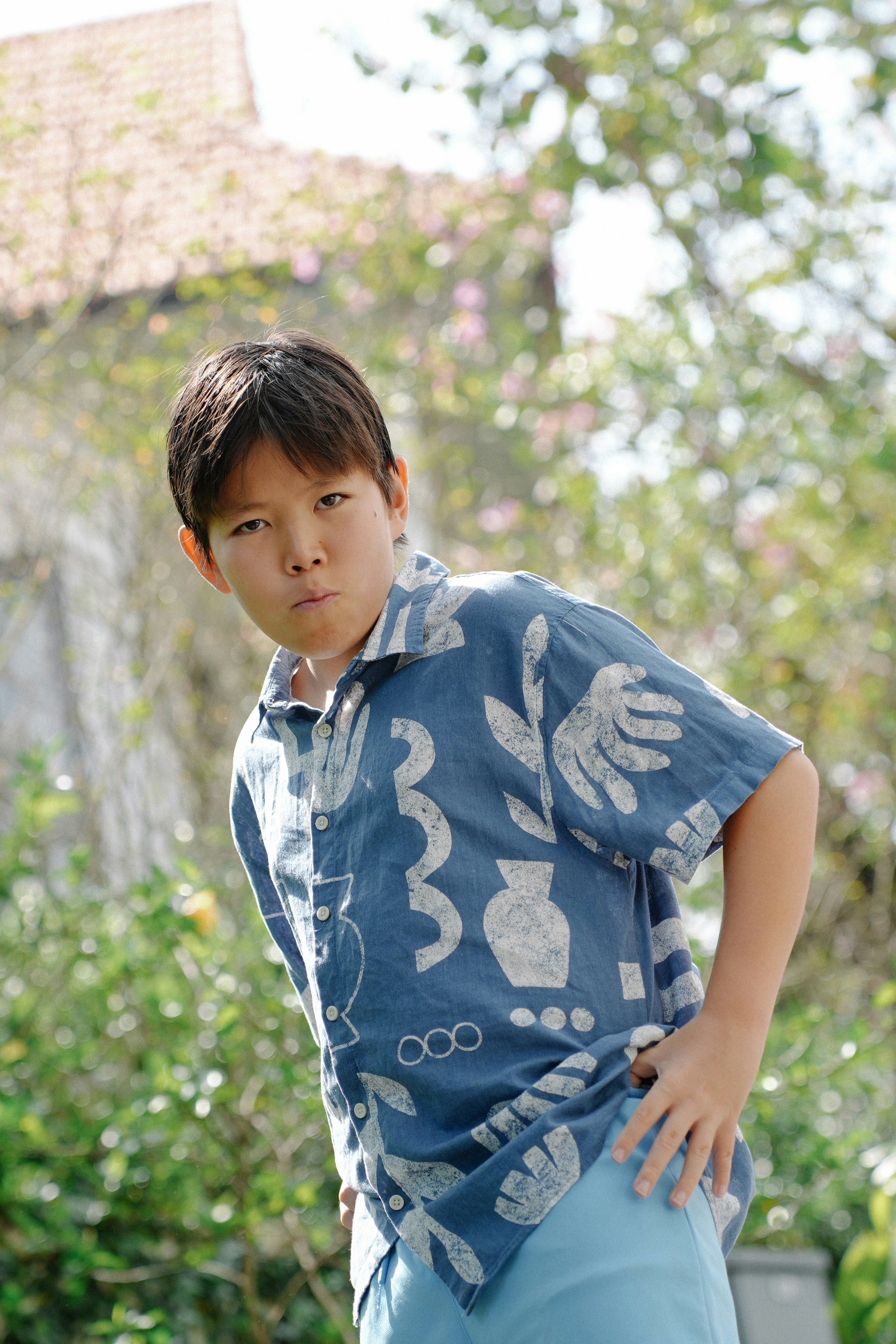 A young boy in a patterned shirt outside.