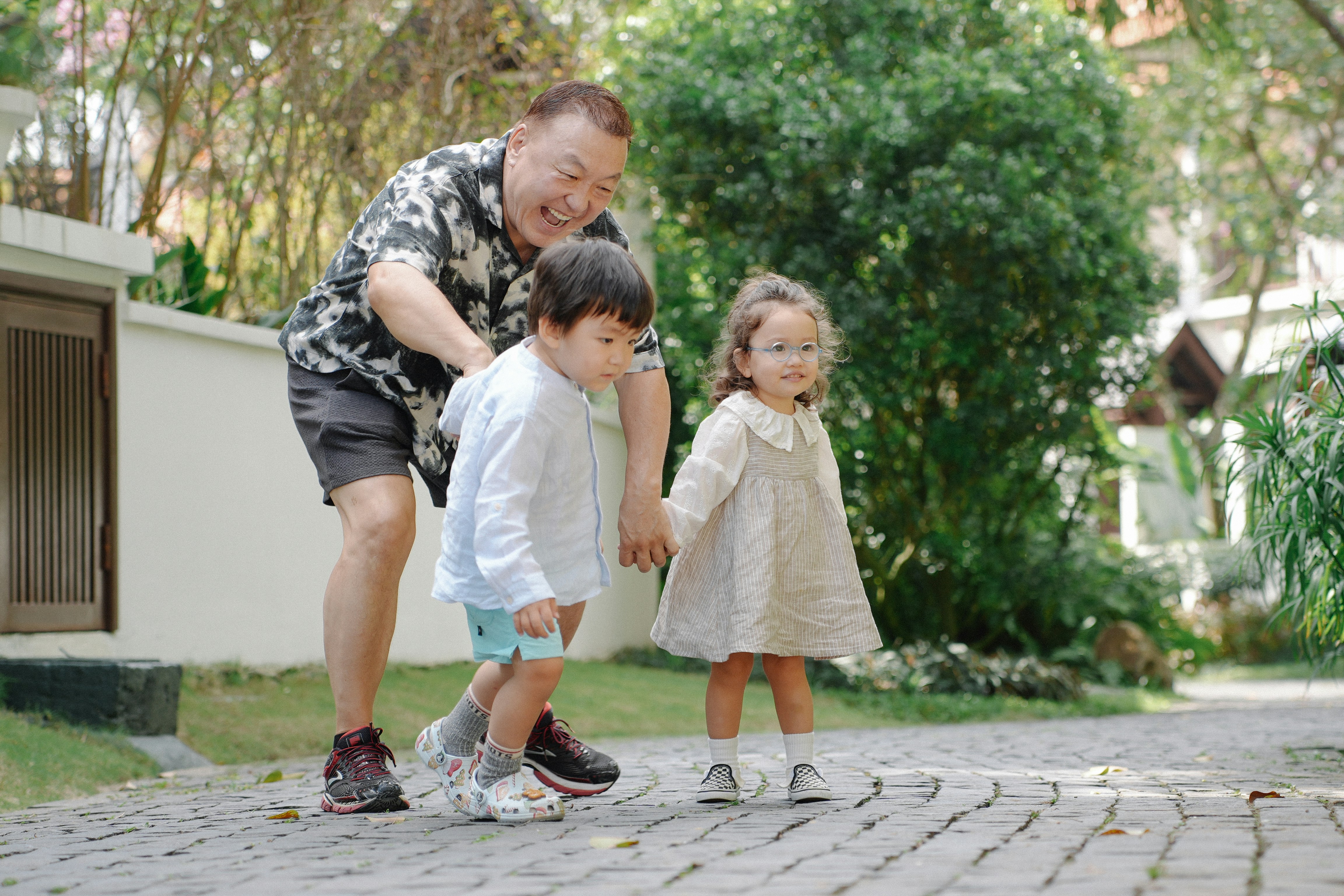 Man with two children walking on a paved path.