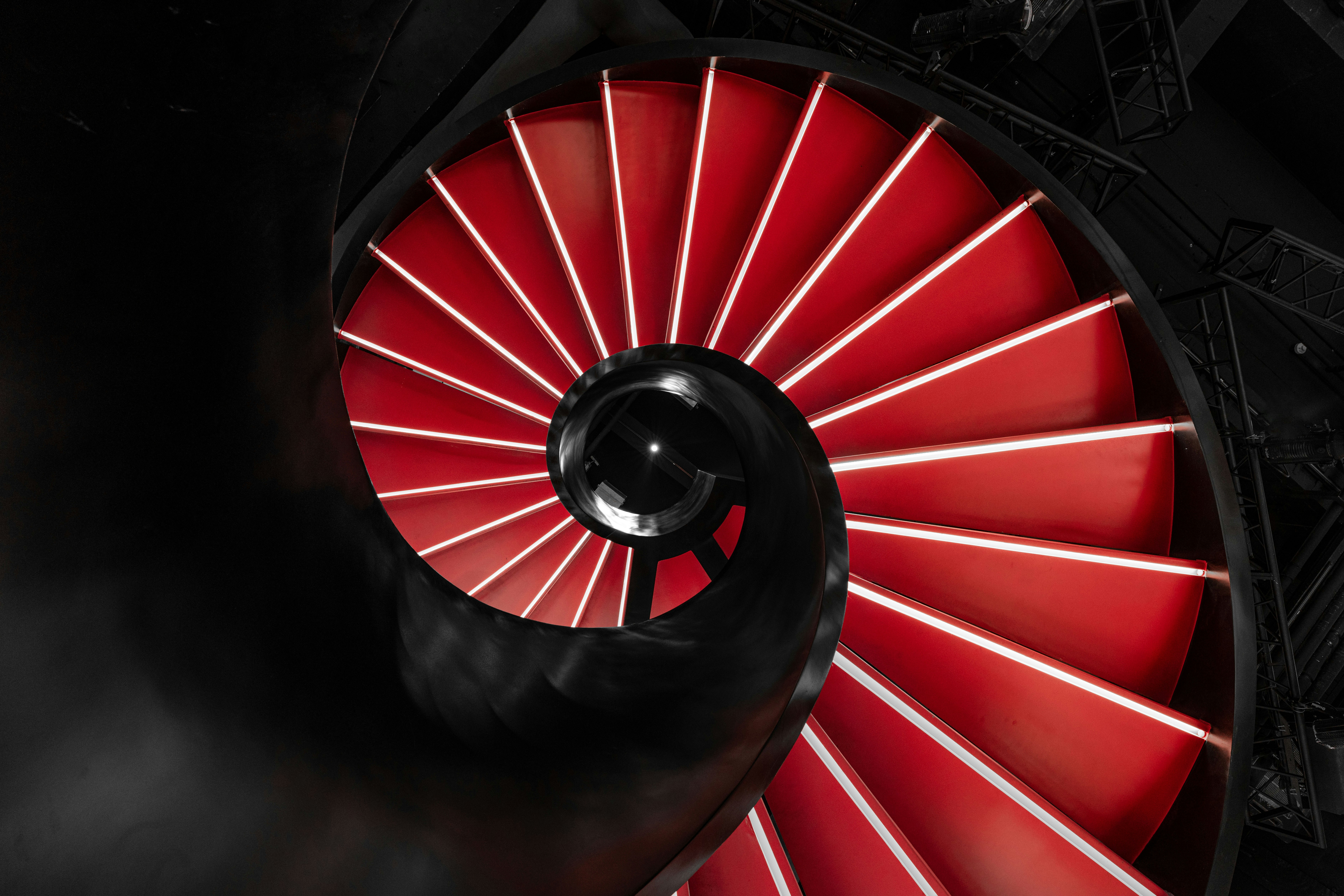 A glowing red spiral staircase descends into darkness.