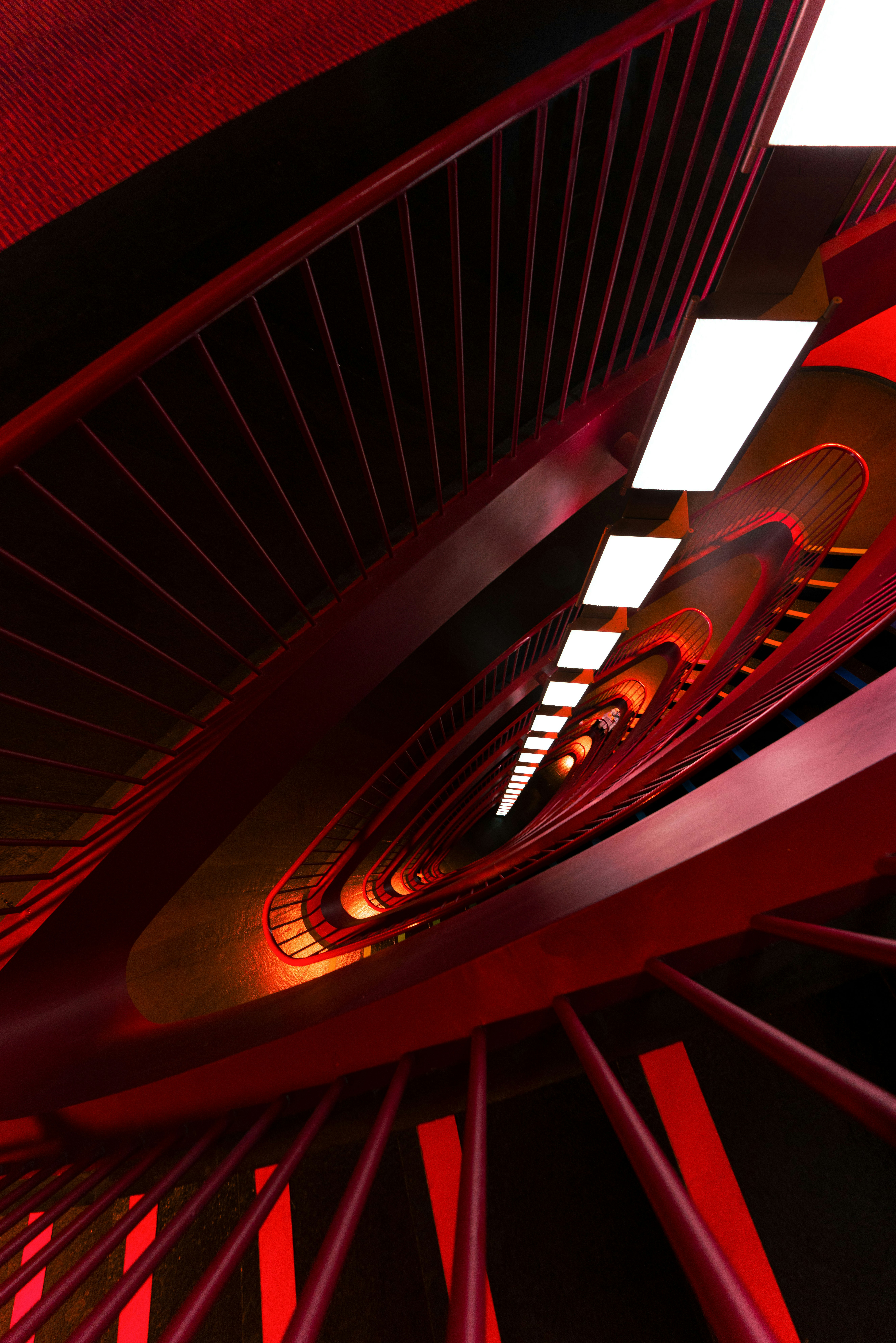 Red spiral staircase with bright white lights above