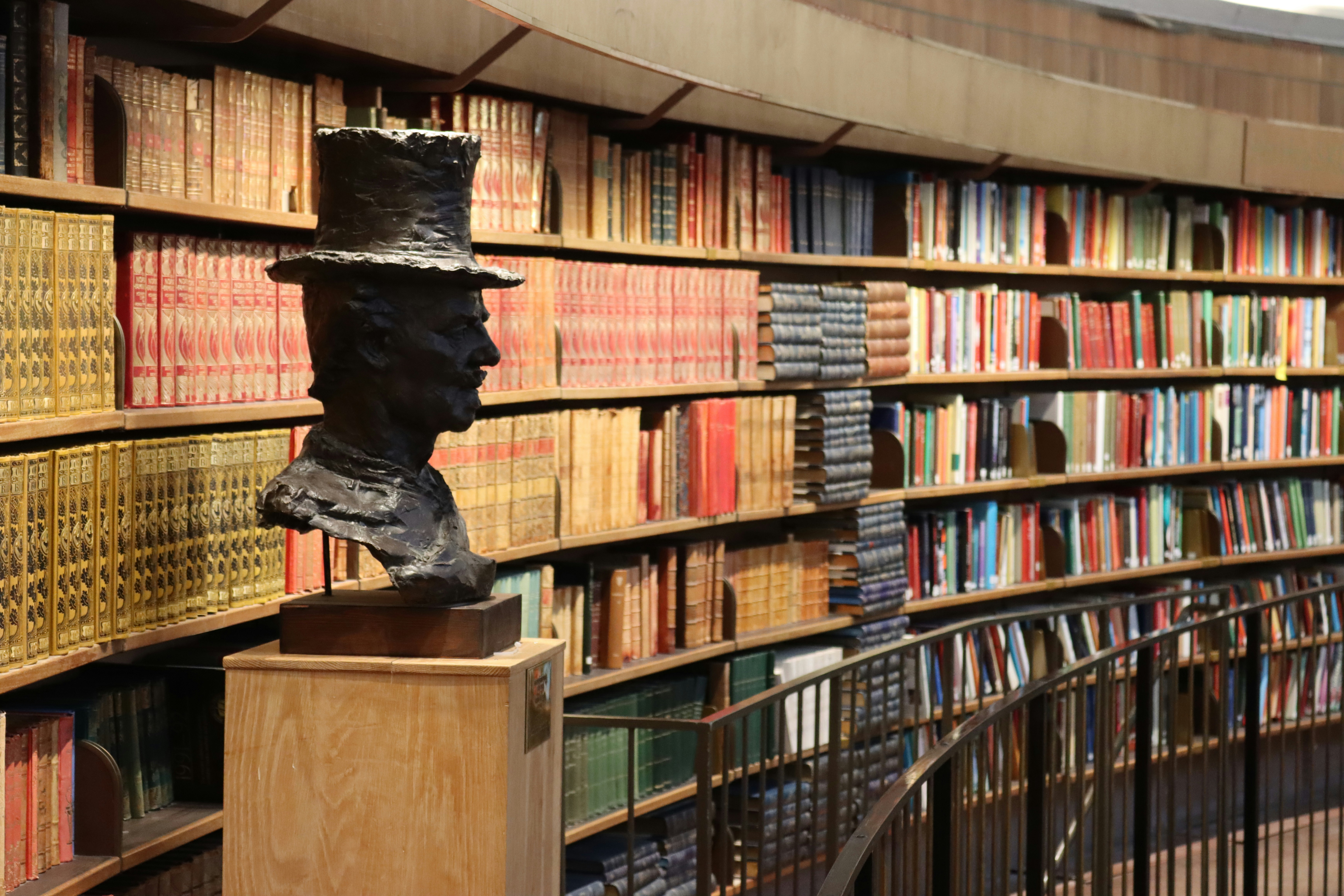 Bust in front of a curved wall of bookshelves