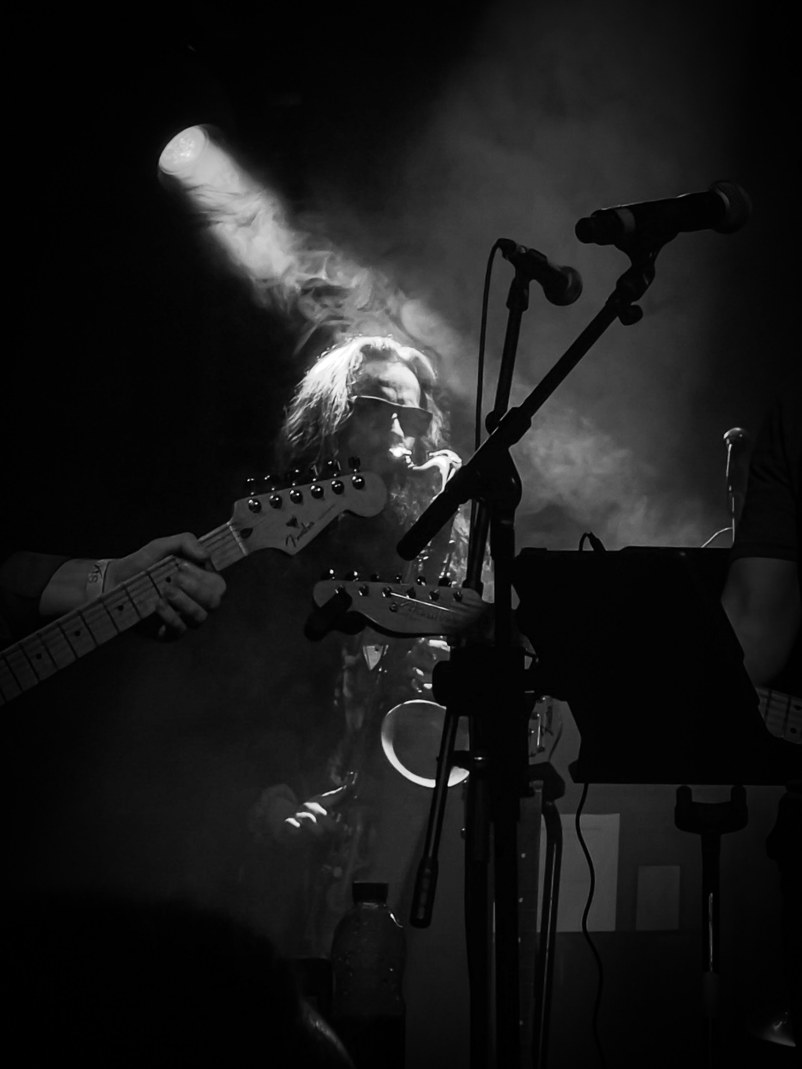 Musician playing guitar on a smoky stage.