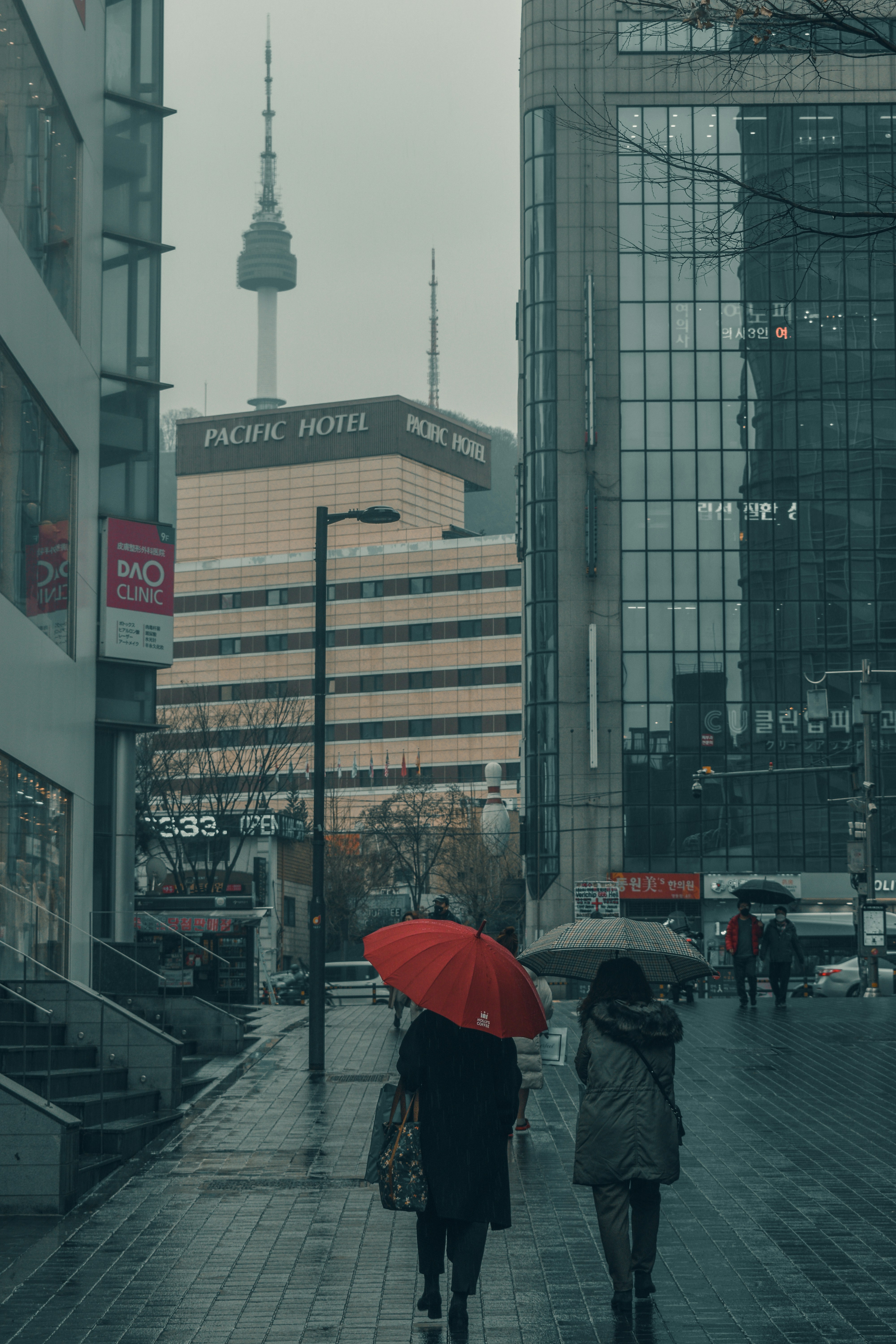People walk with umbrellas on a rainy city street.