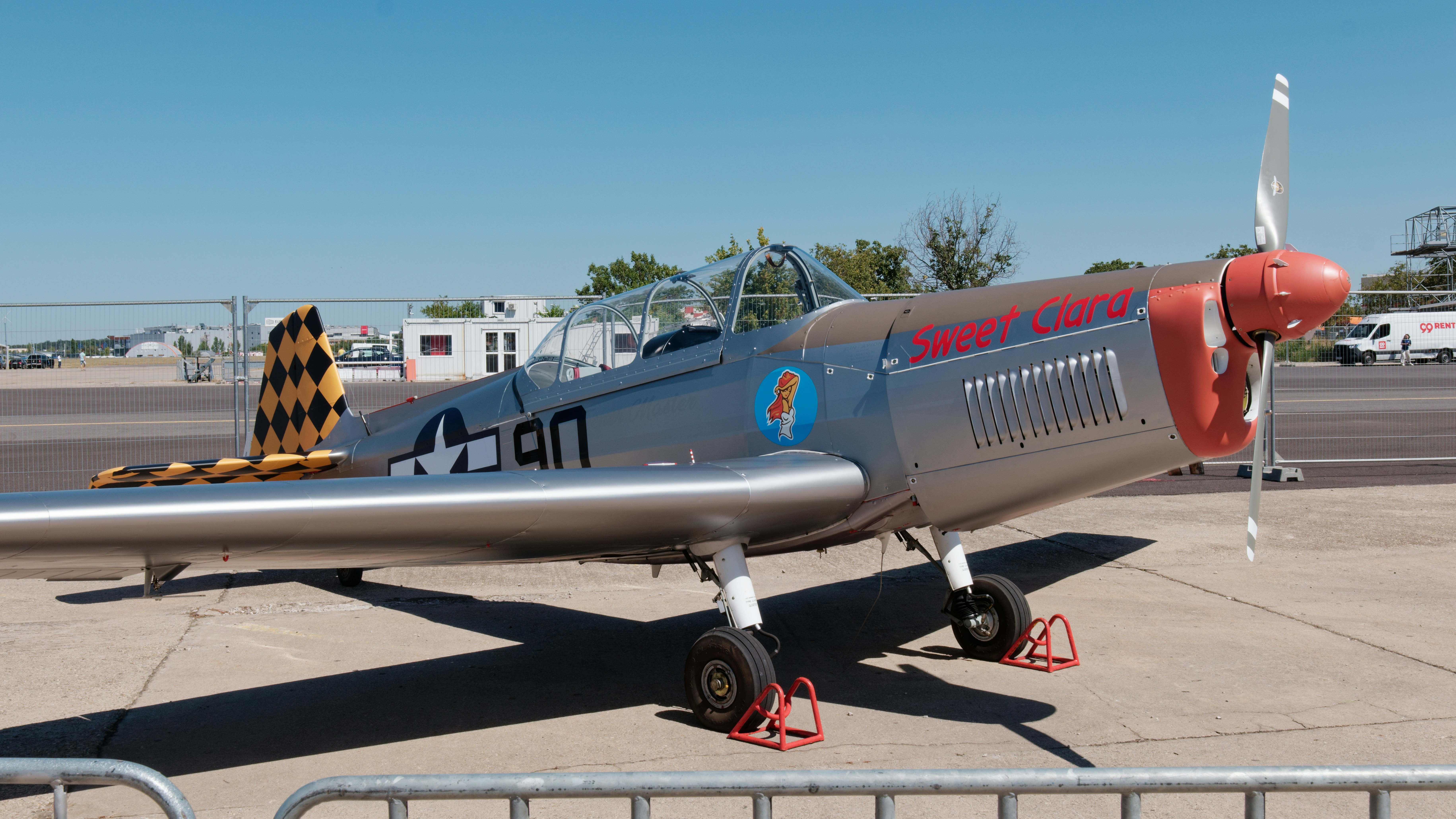 Silver vintage airplane with red nose and tail.