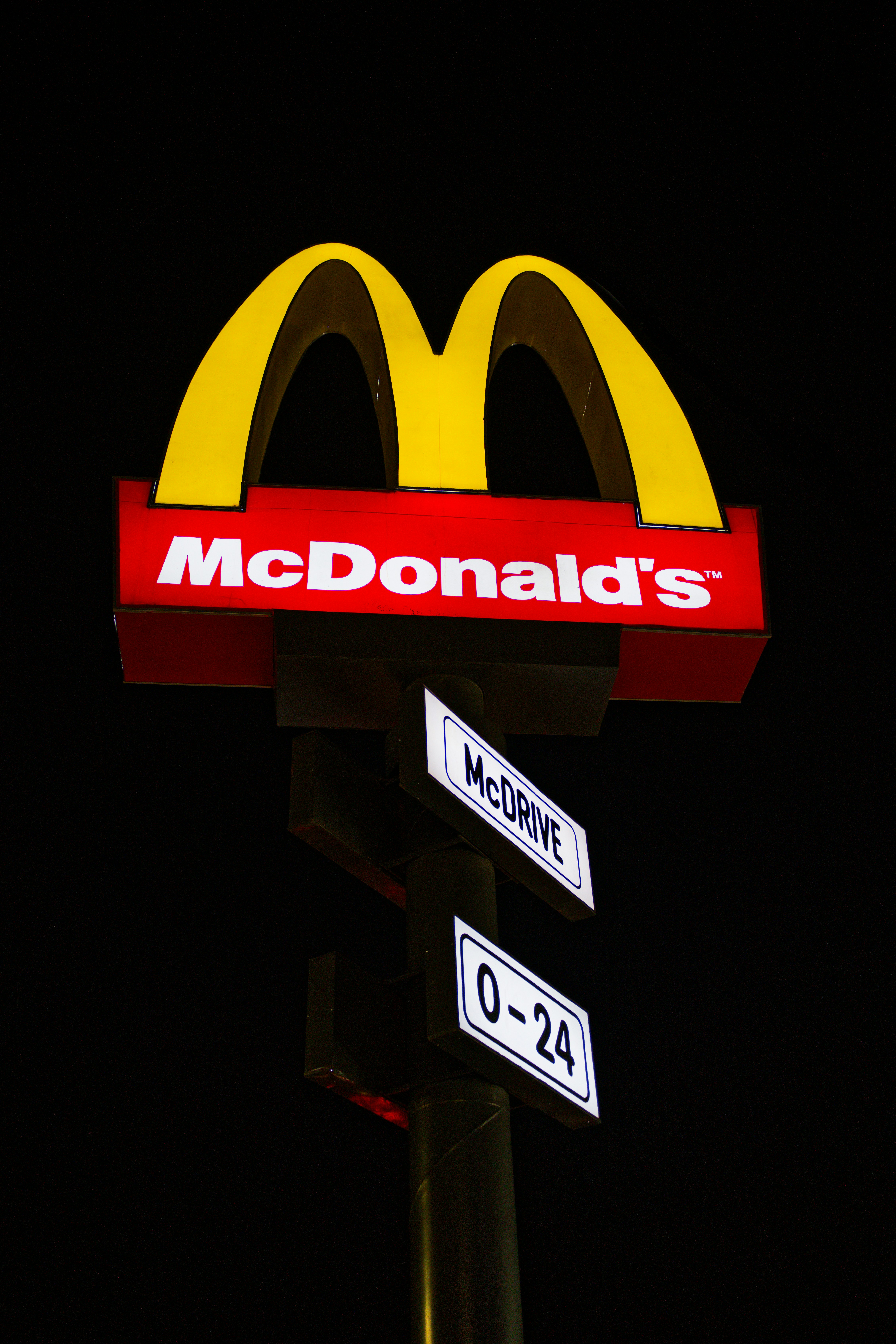 Mcdonald's sign at night with drive-thru hours
