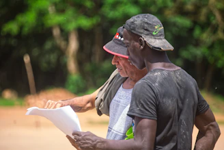 Two men looking at a document outdoors