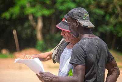 Two men looking at a document outdoors