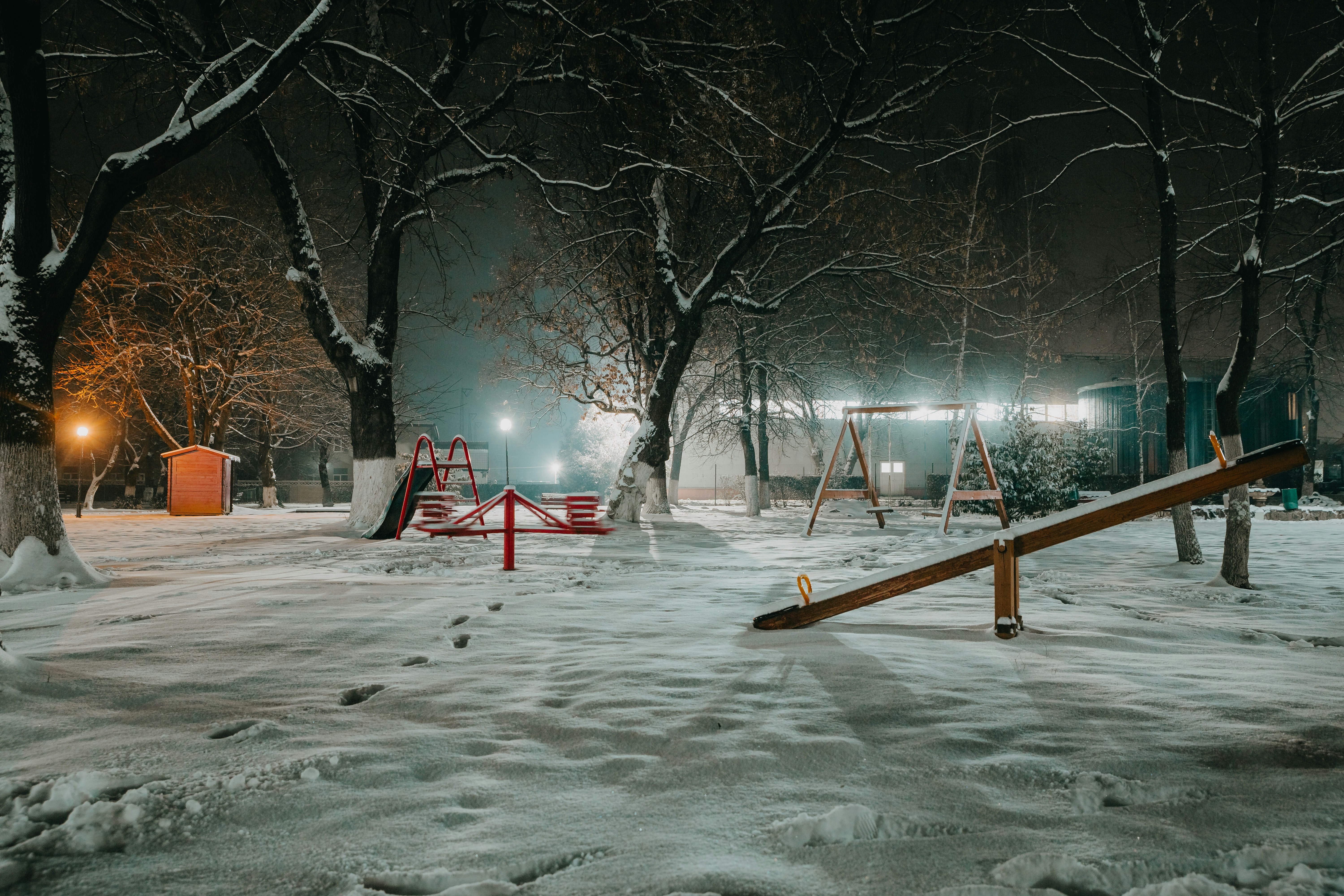 e3036f65e35e86e6 - Snow-covered playground with swings and seesaw at night
