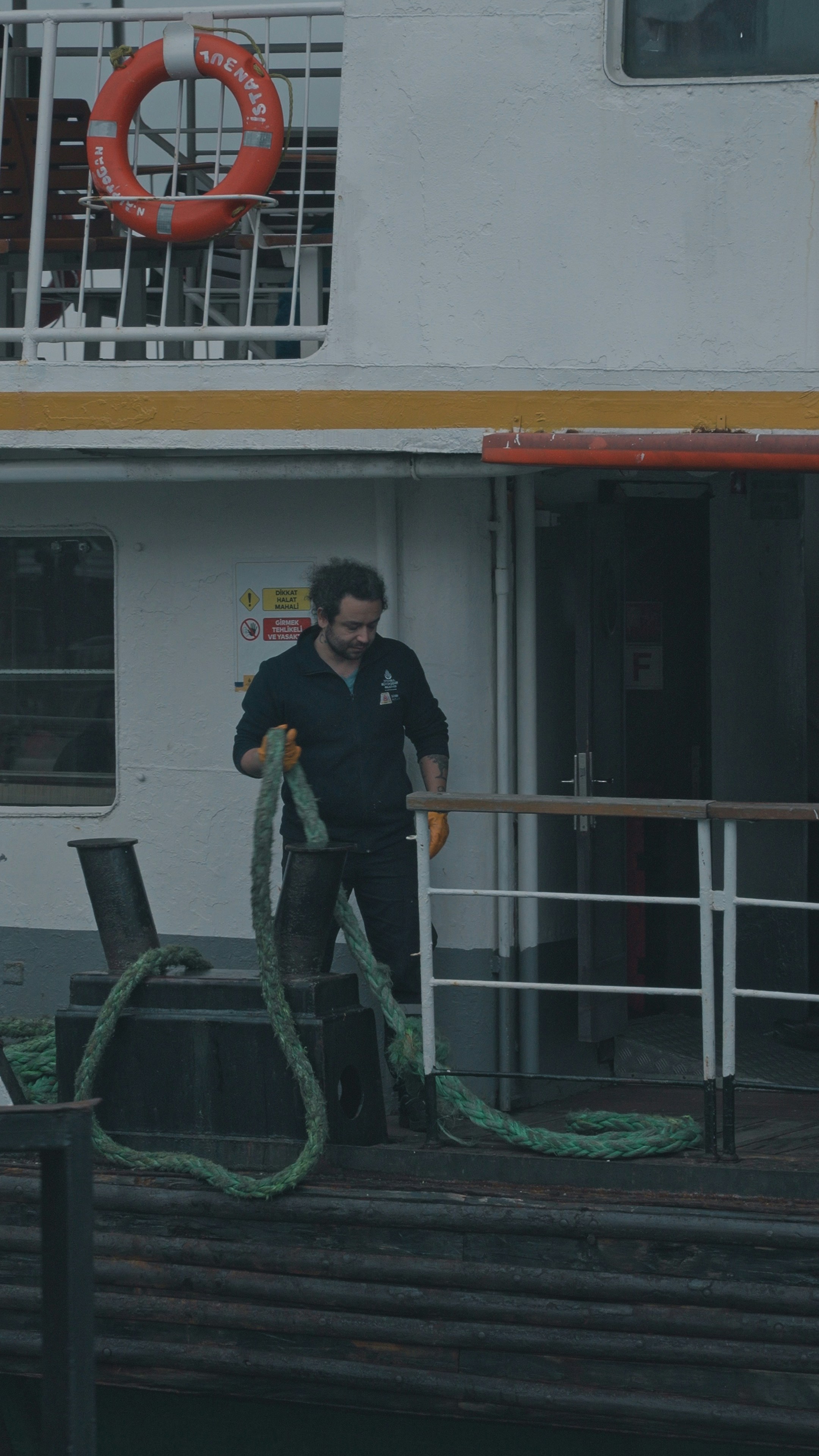 Man handling a thick rope on a boat deck.