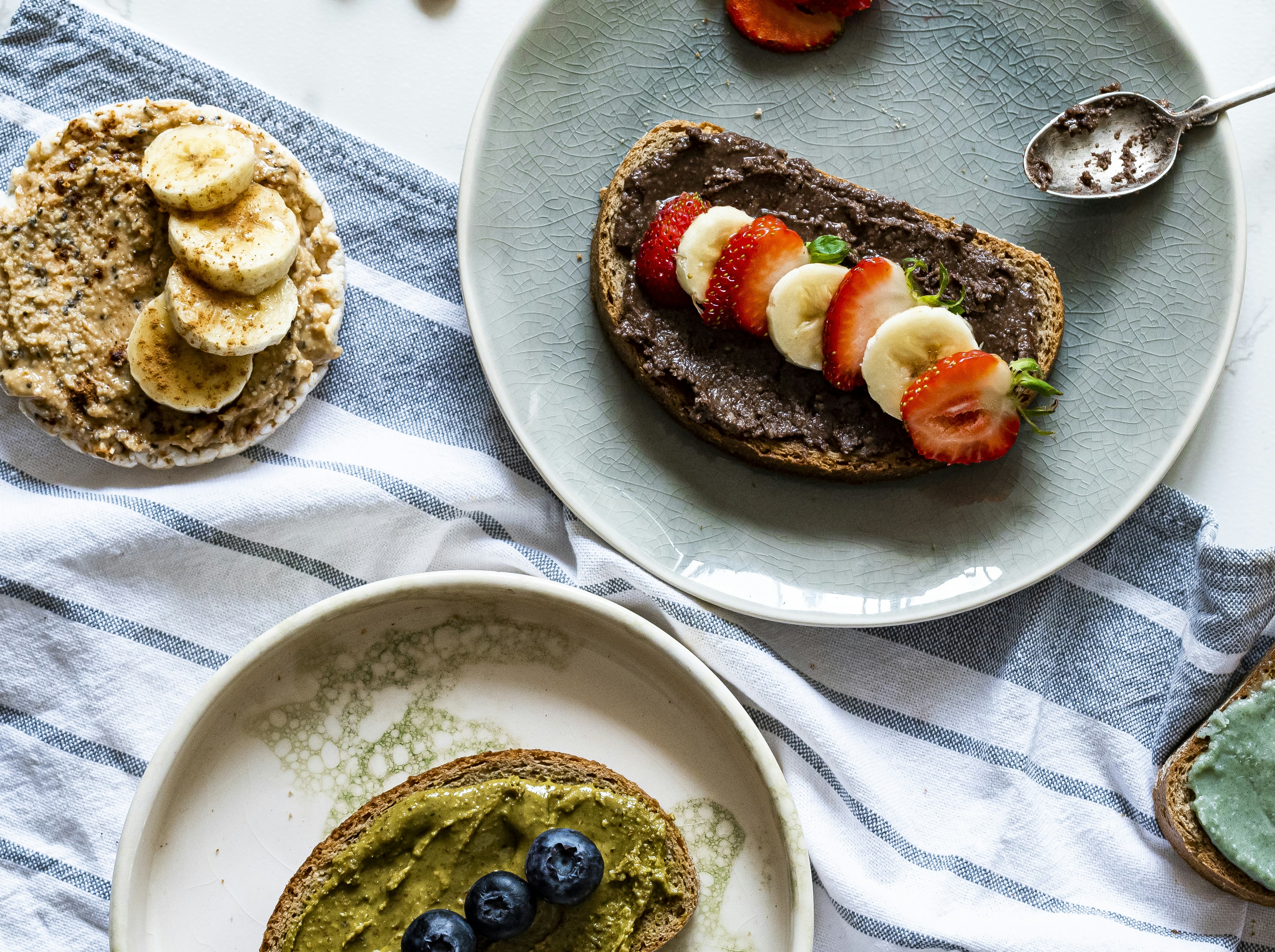 Toasts with fruit and spreads on a striped cloth.