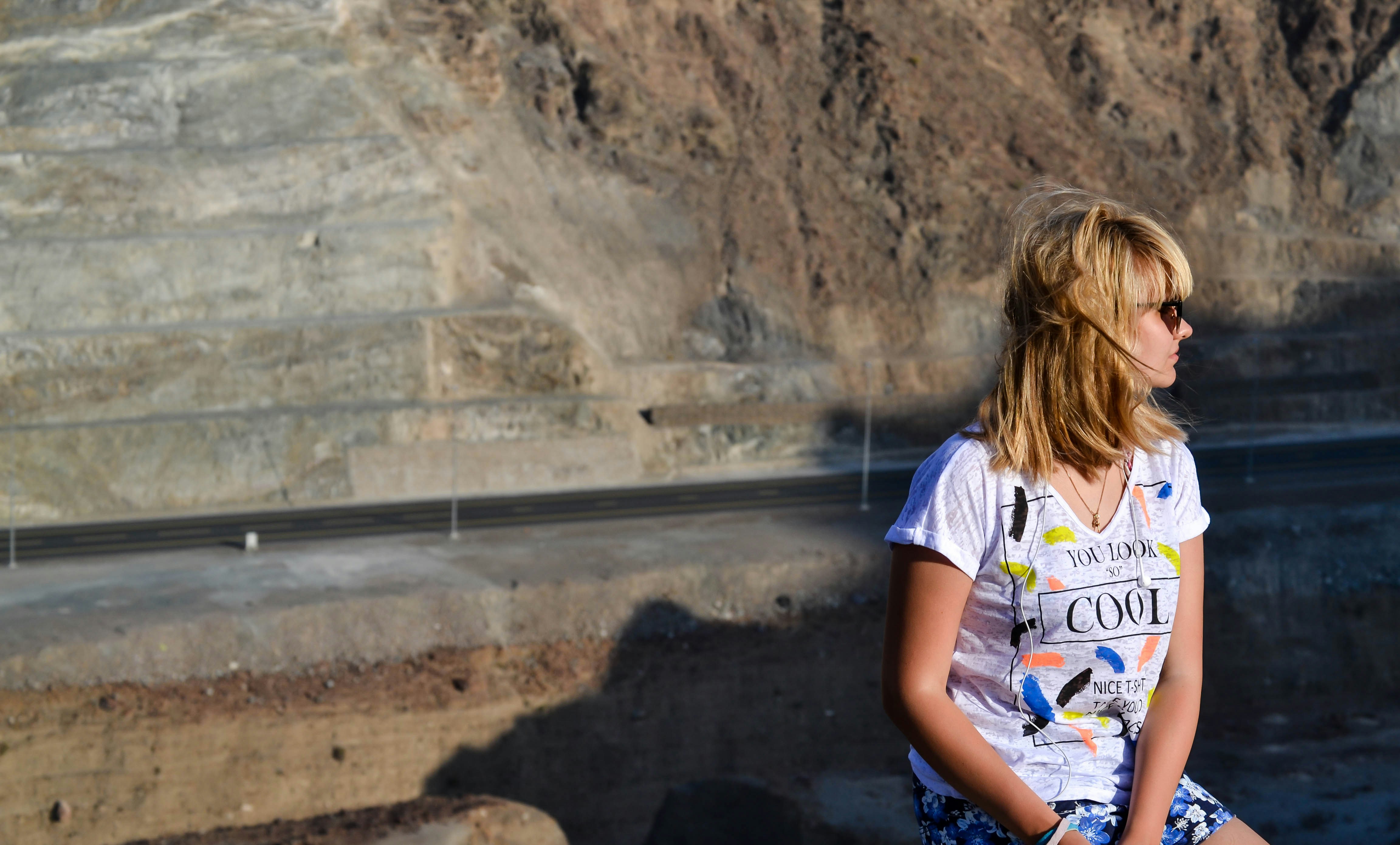 Wanita duduk di dekat tebing berbatu saat matahari terbenam