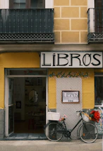 A bicycle parked outside a bookstore entrance.