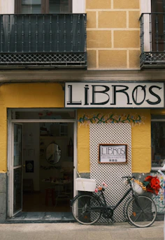 A bicycle parked outside a bookstore entrance.