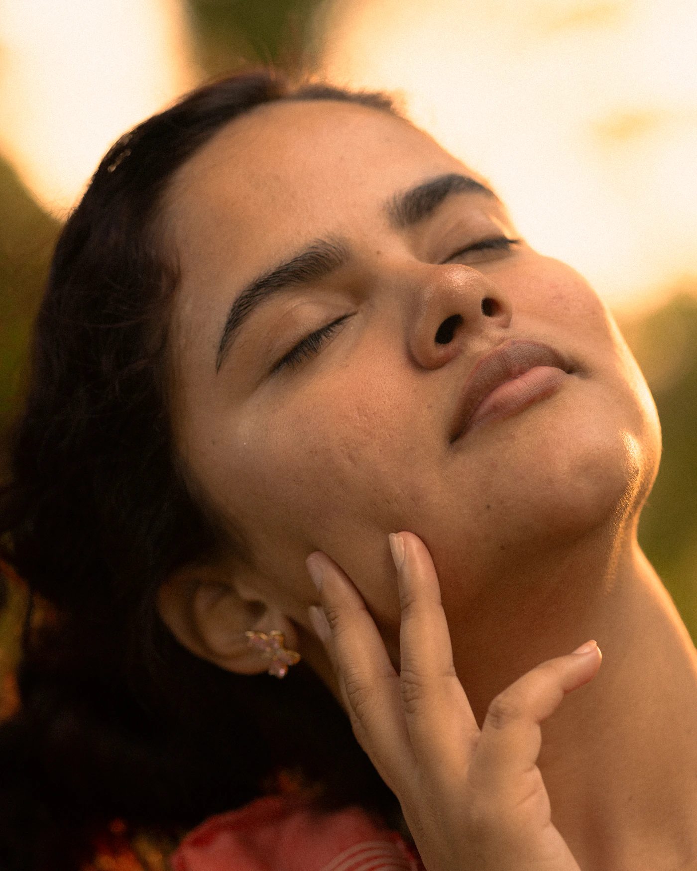 Woman with eyes closed gently touching her own face, representing the calm, refined feeling after a Pore Cleansing Facial session